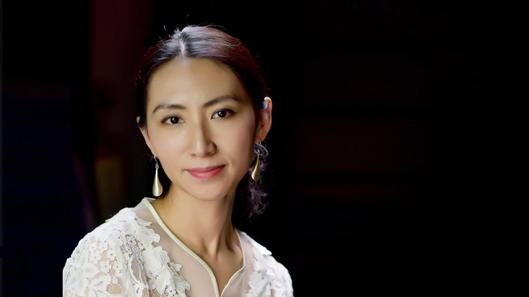 Yinuo Li in a white dress with a black background