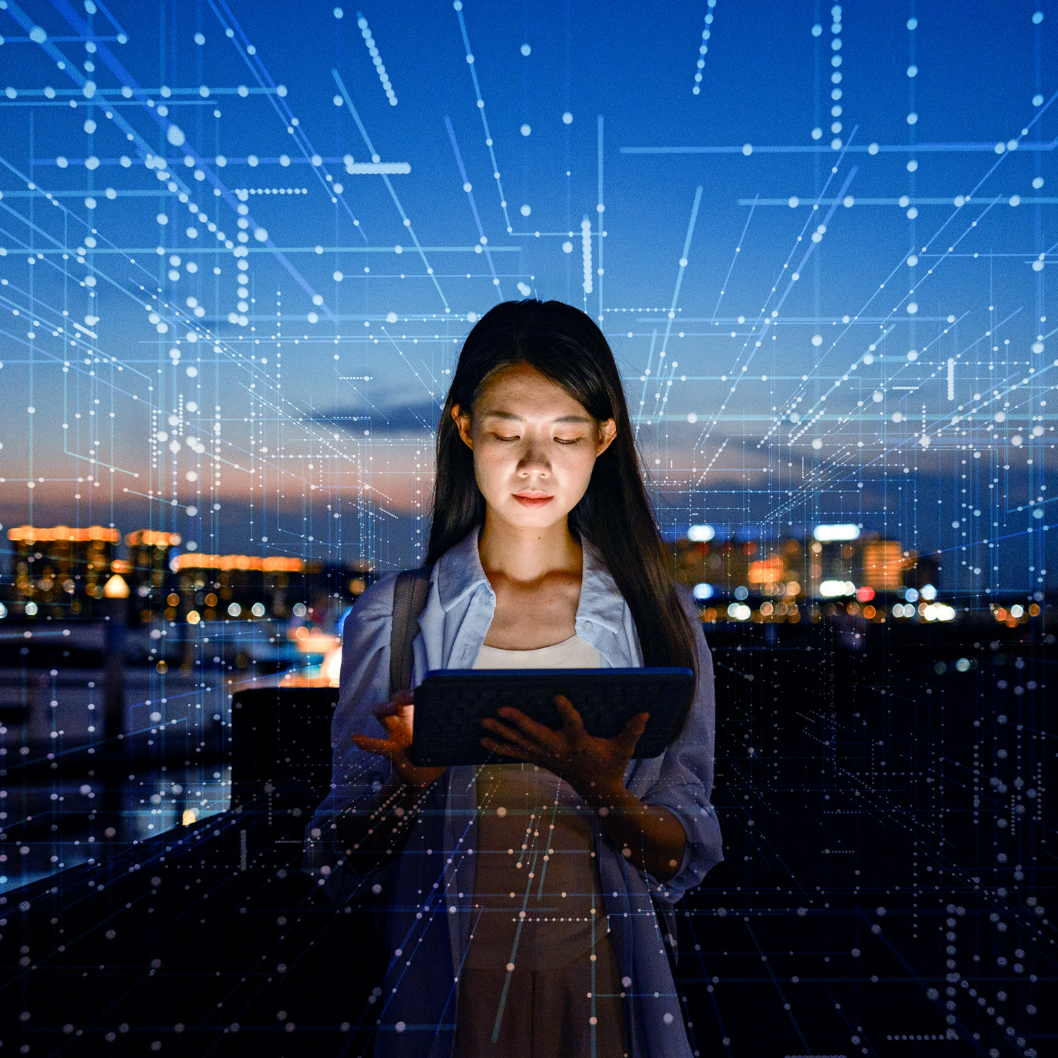 A woman stands outdoors at dusk, focused on a tablet in her hands with a city skyline glowing in the background. Digital lines and data-like patterns overlay the scene, suggesting connectivity, technology, and data flow.
