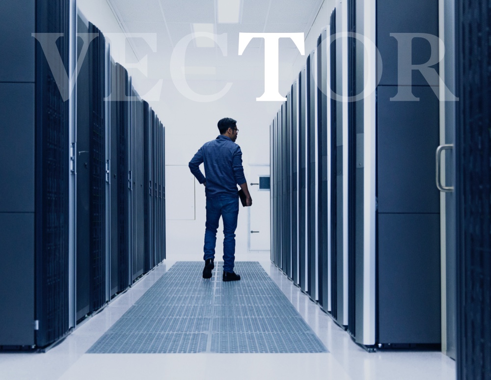 Man standing amongst rows of cubicles with the T highlighted in VECTOR text overlay