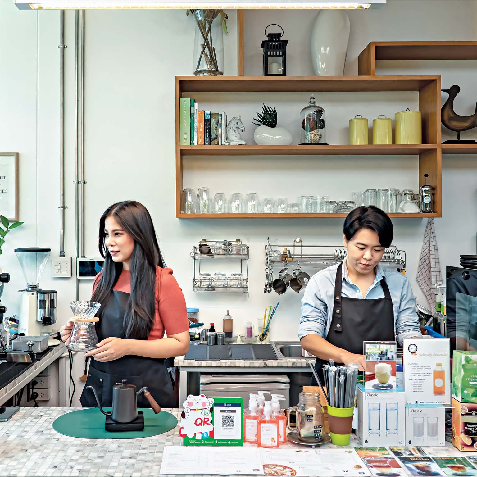 Two employees operating a modern café with professional coffee equipment and organized workspace