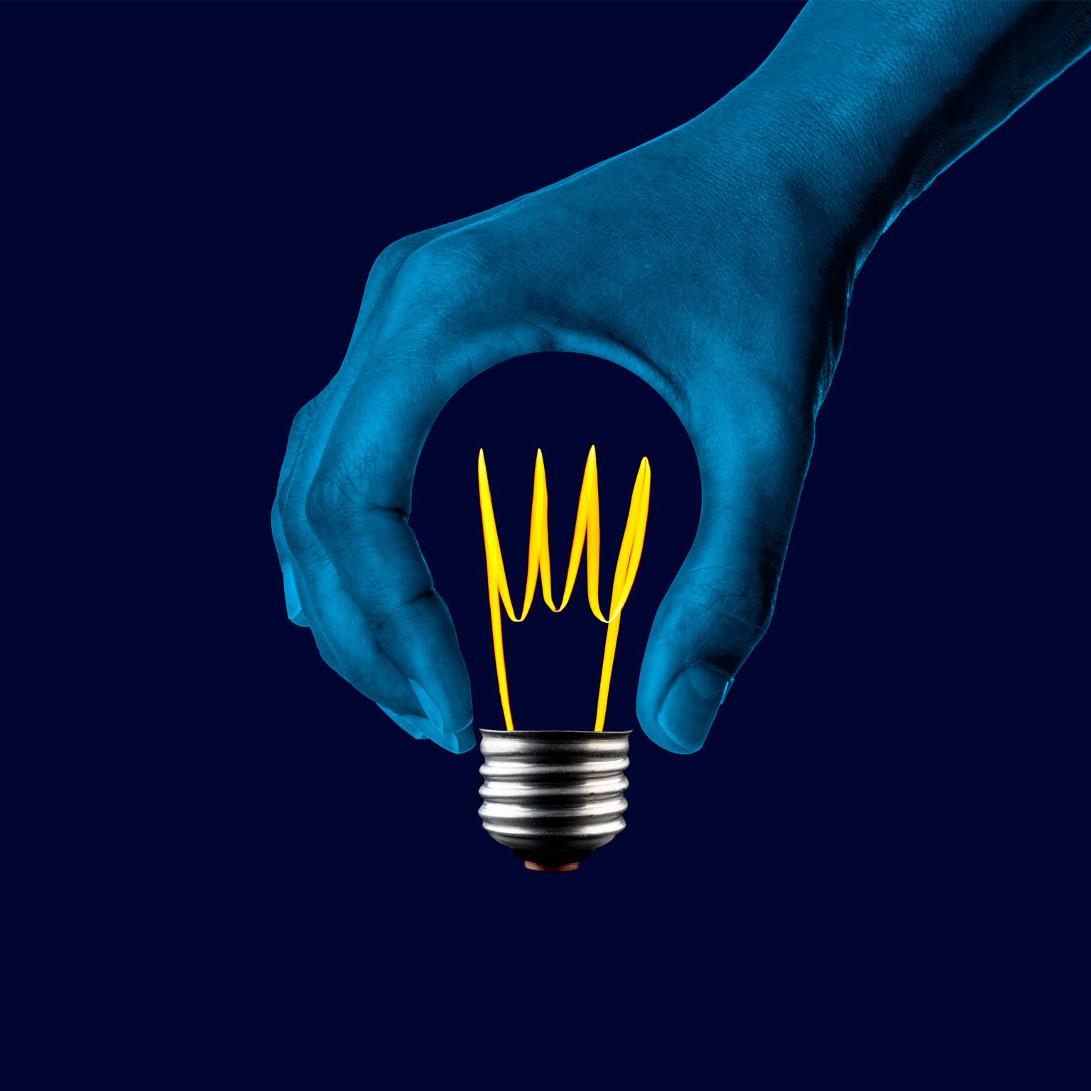 A thumb and an index finger form a circular void, resembling the shape of a light bulb but without the glass component. Inside this empty space, a bright filament and the gleaming metal base of the light bulb are visible.