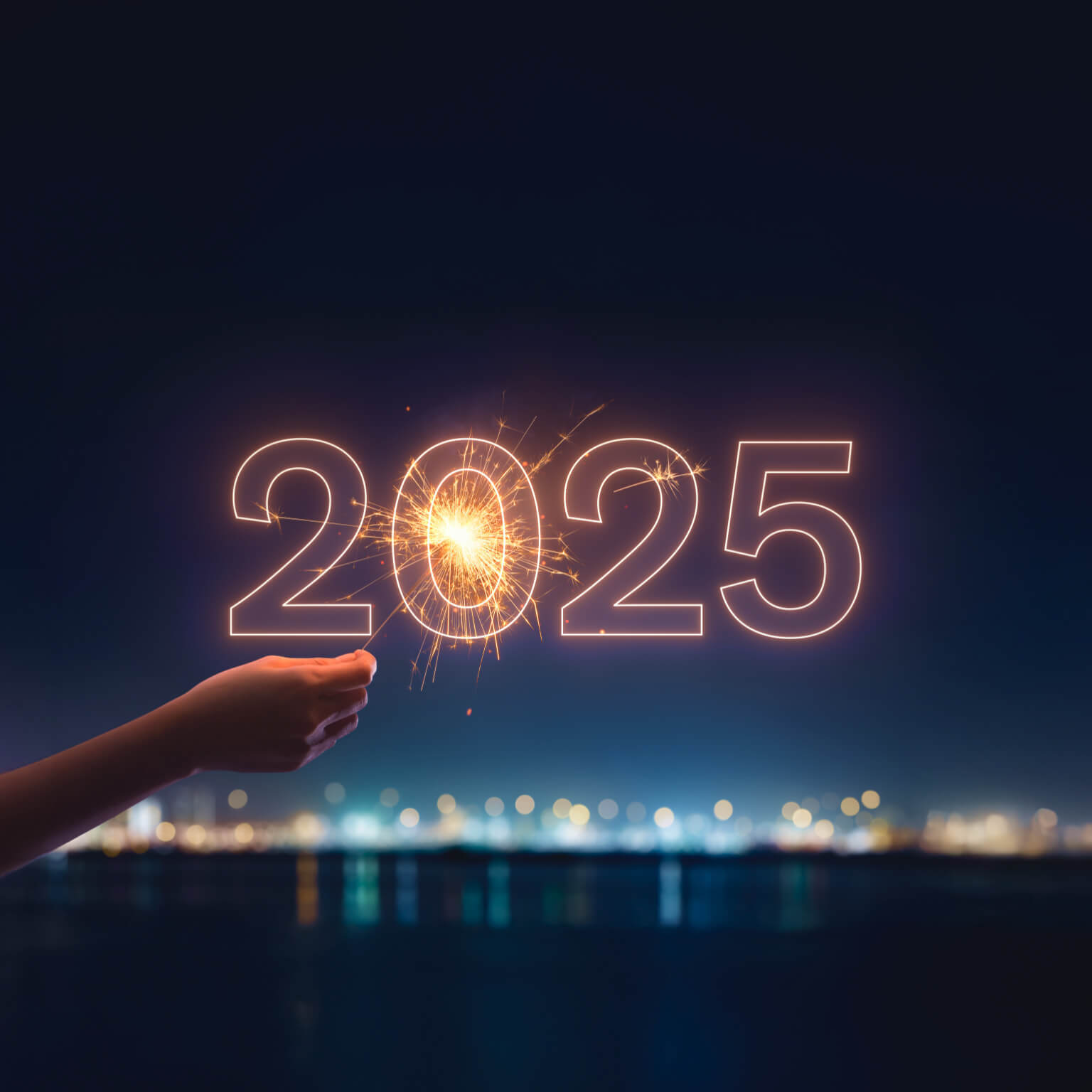 Hand holding sparkler behind 2025 sign