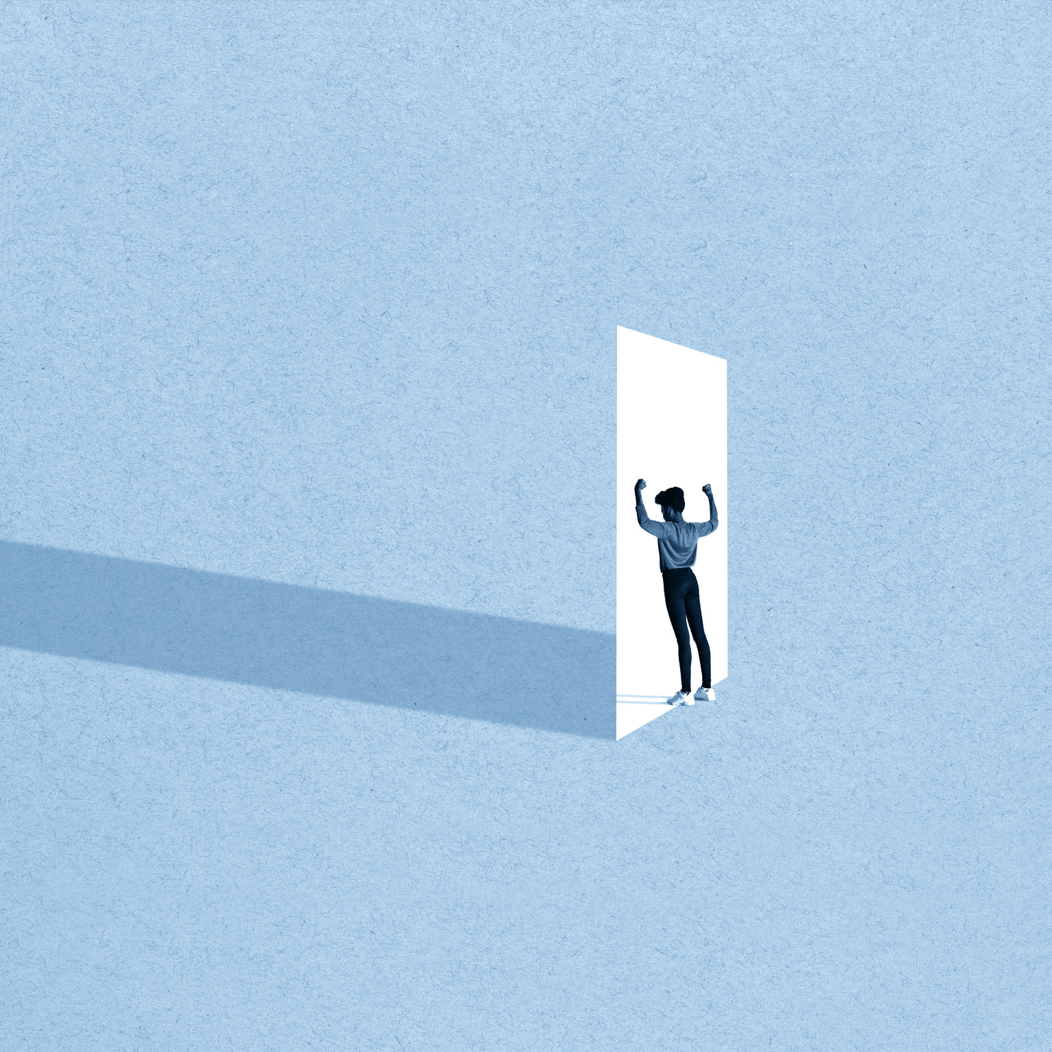 Full length of young woman flexing muscles while standing in front of white doorway against blue background