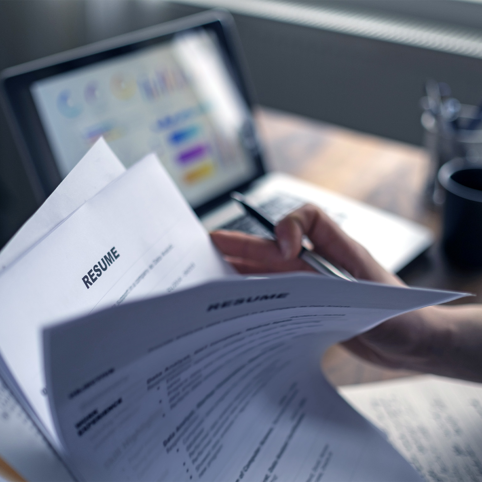 HR employee flipping through a stack of printed resumes