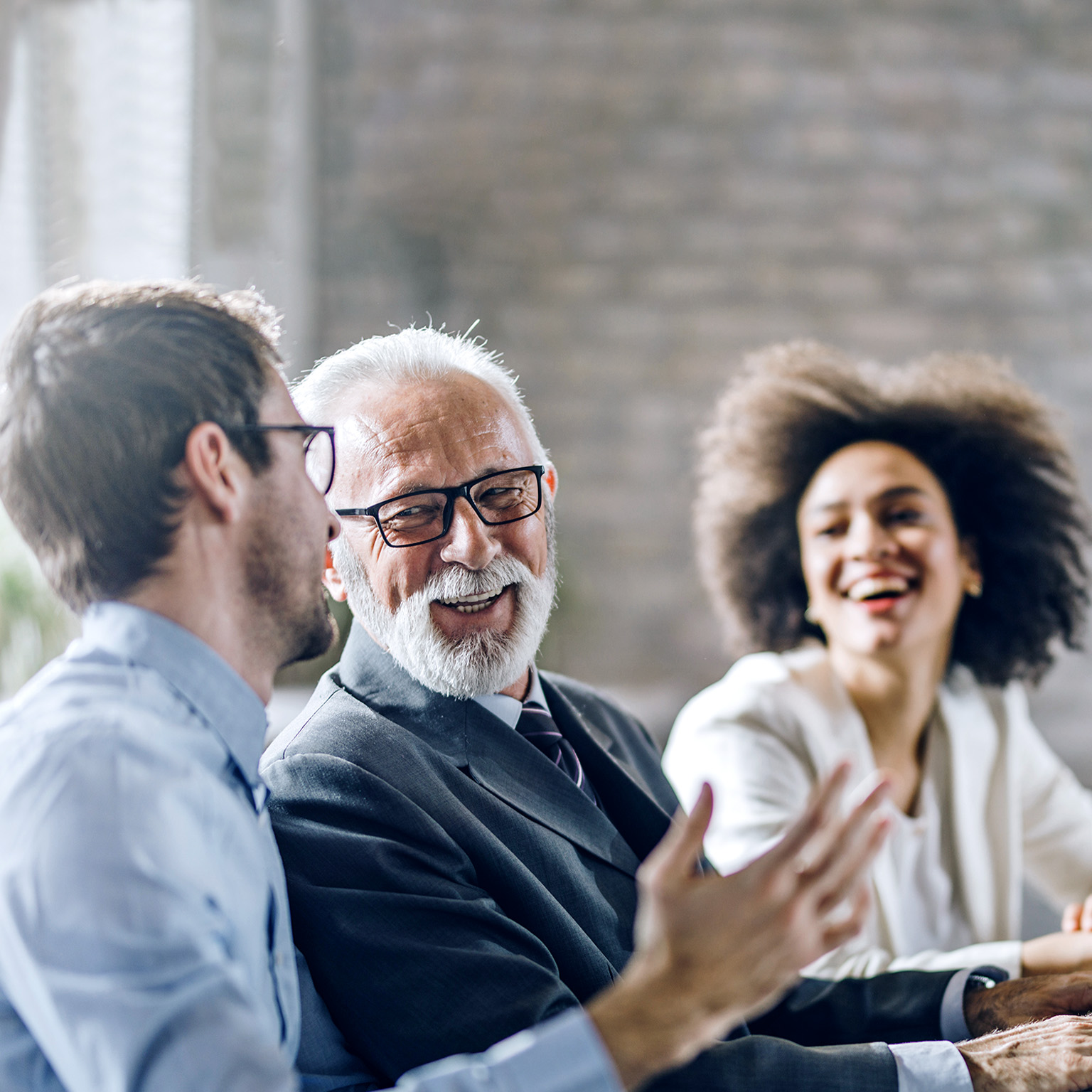 Smiling diverse business colleagues of different ages talking while working at a PC in the office.