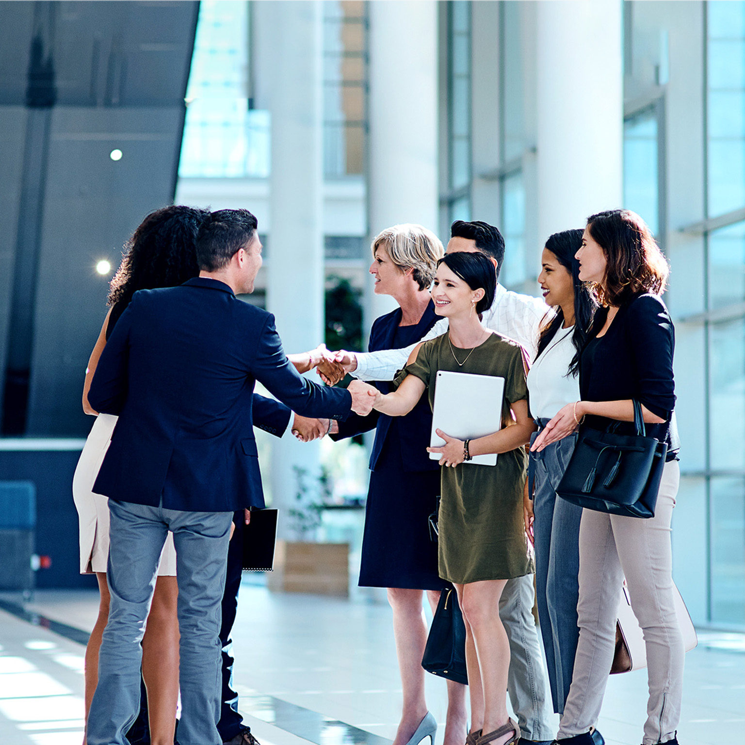 A group of businesspeople greeting each other inside of a office