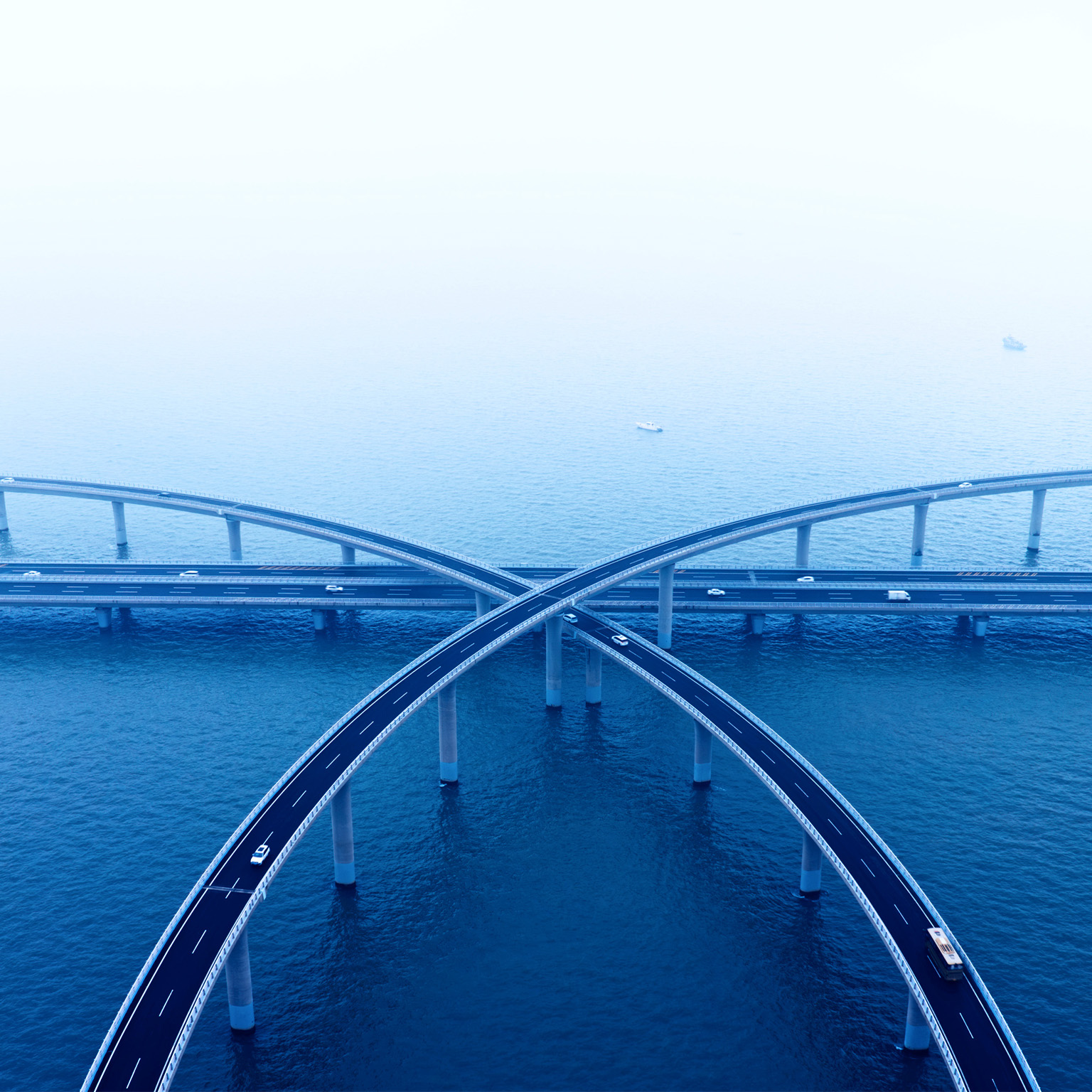 Aerial view of intersecting highway bridges over water with light traffic.
