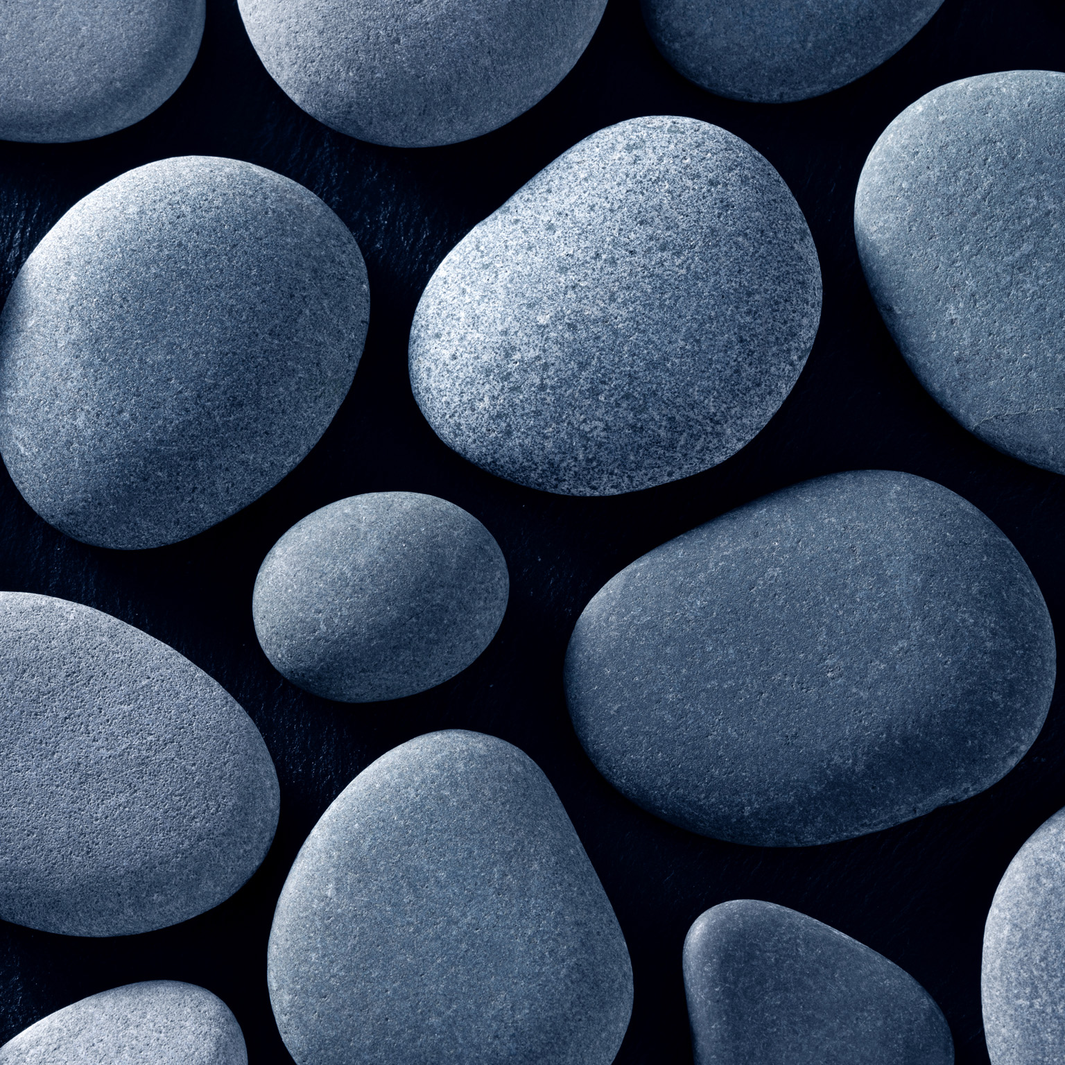 Smooth, gray river stones on a black background.