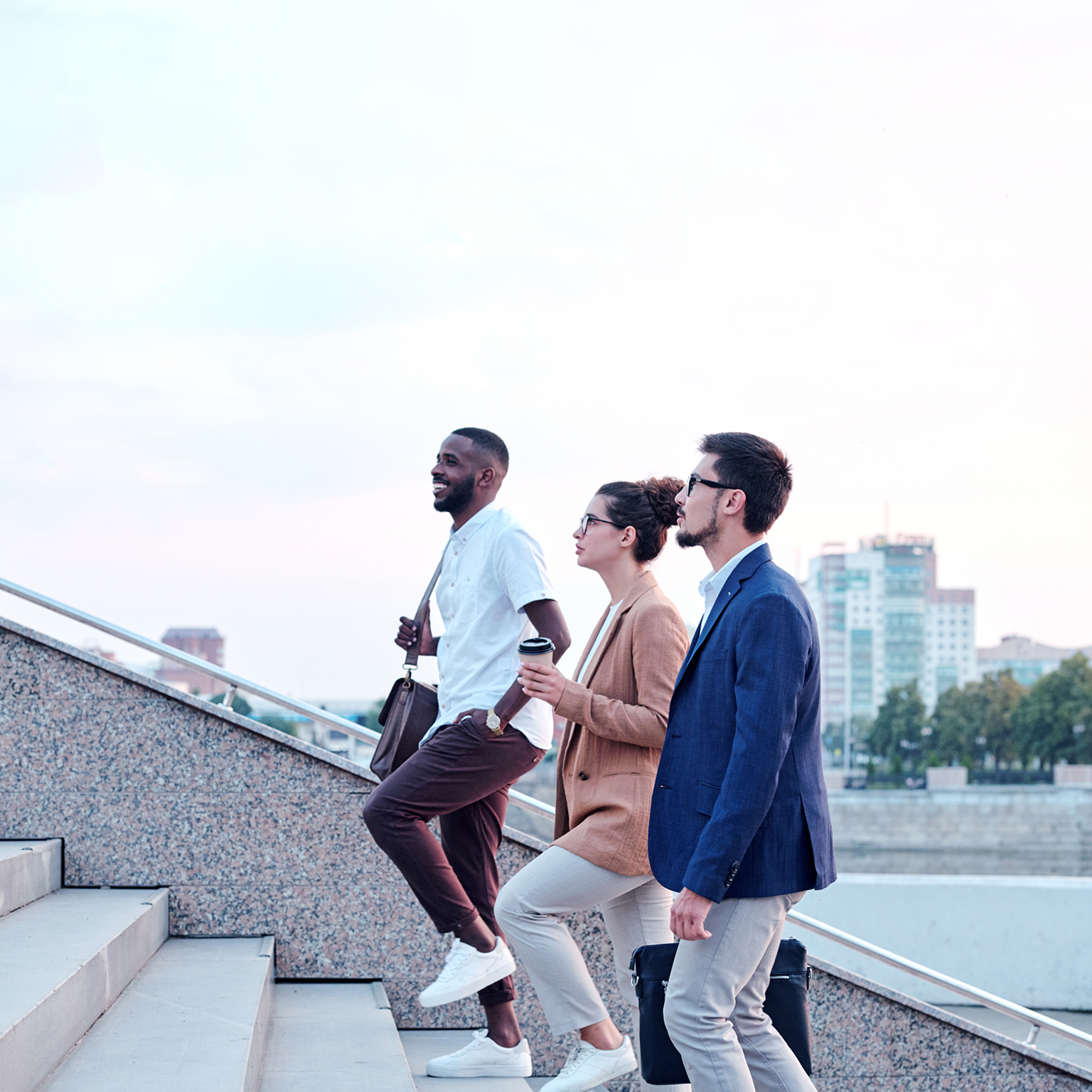 Side view of a confident multi-ethnic group of young professionals chatting while walking up a flight of stairs