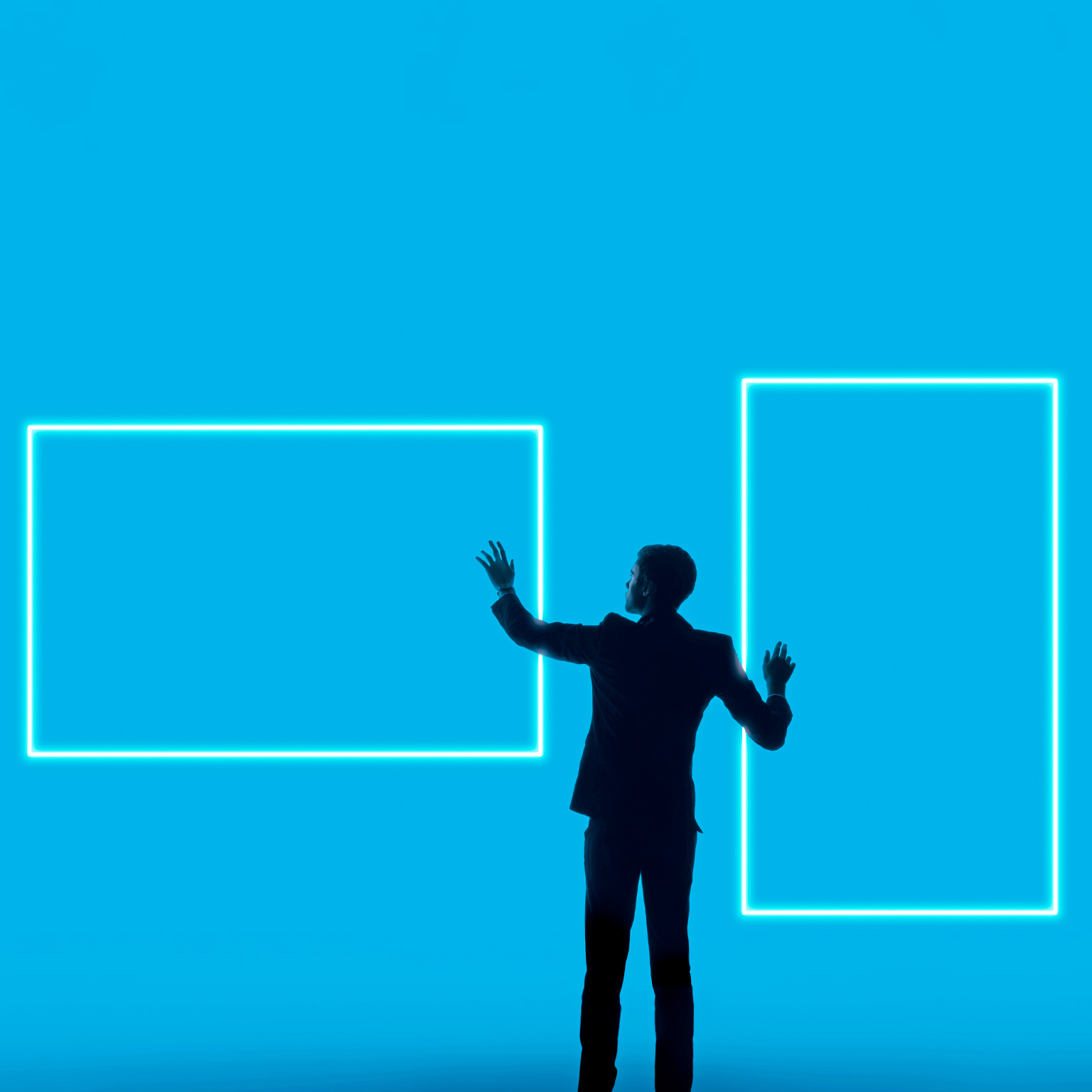 A silhouetted man in a suit stands against a bright blue background, reaching toward two glowing rectangular outlines that resemble digital screens or frames.