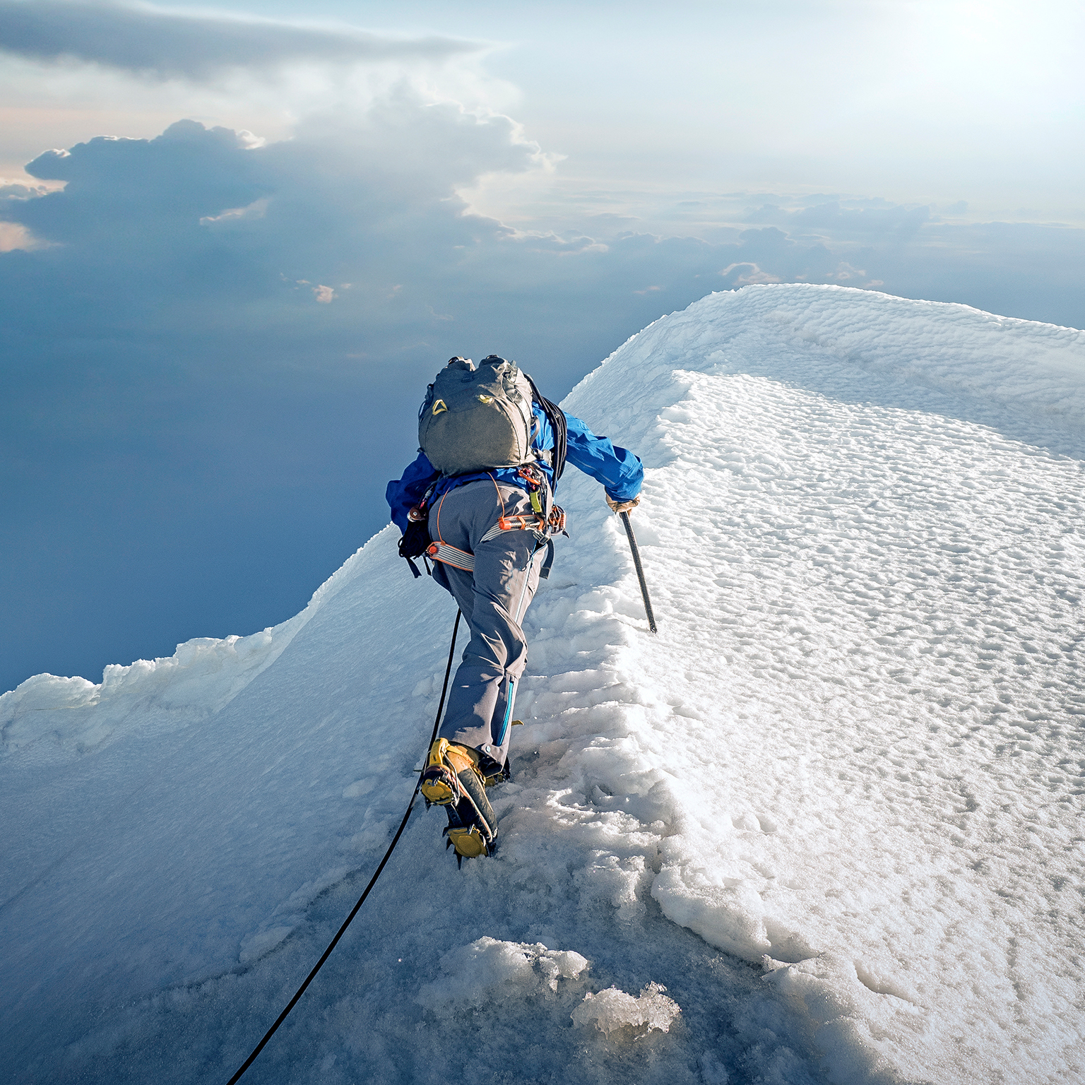 A lone climber ascending a snowy ridge in the Alps