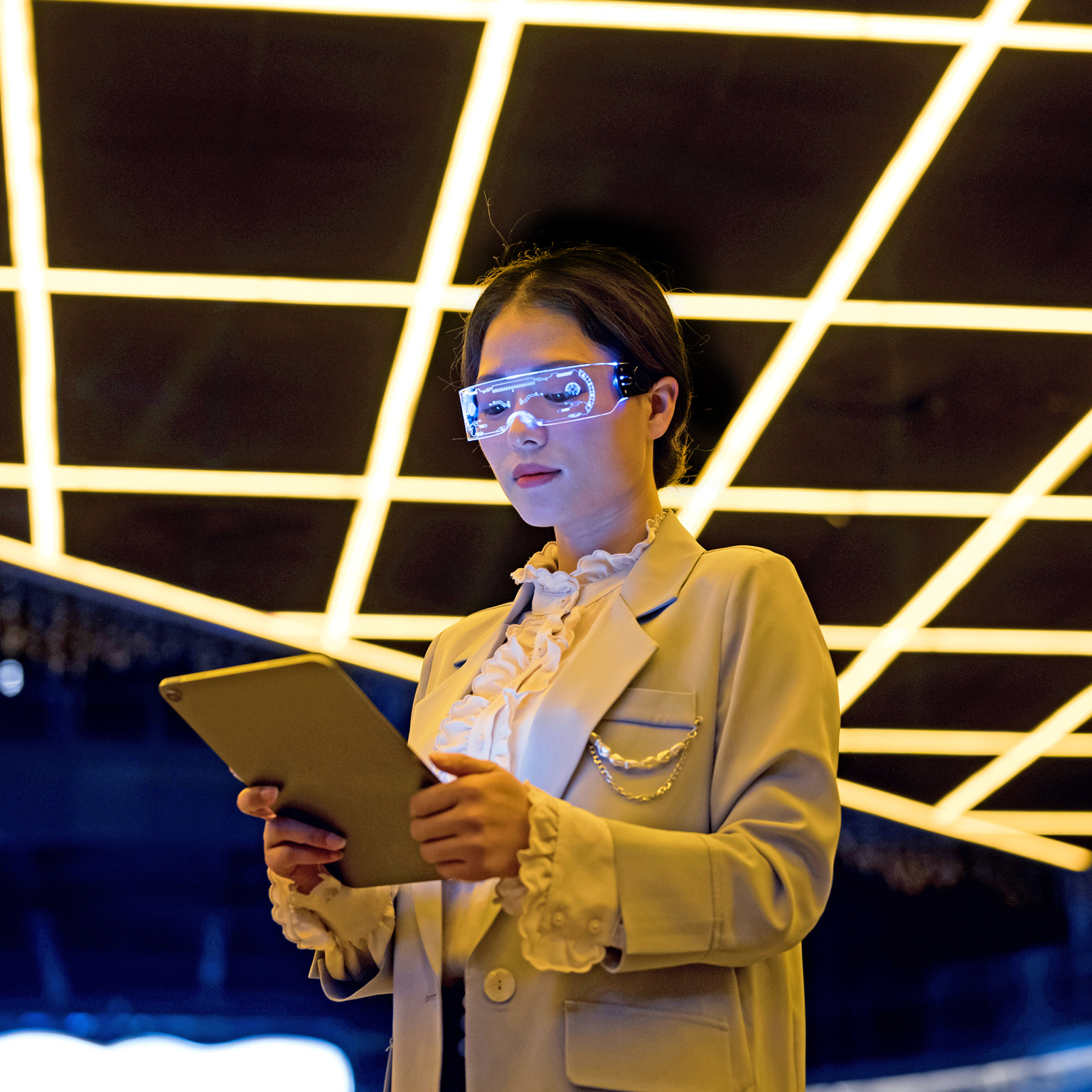 Image of a person wearing tech glasses and a lab coat looking at a tablet.