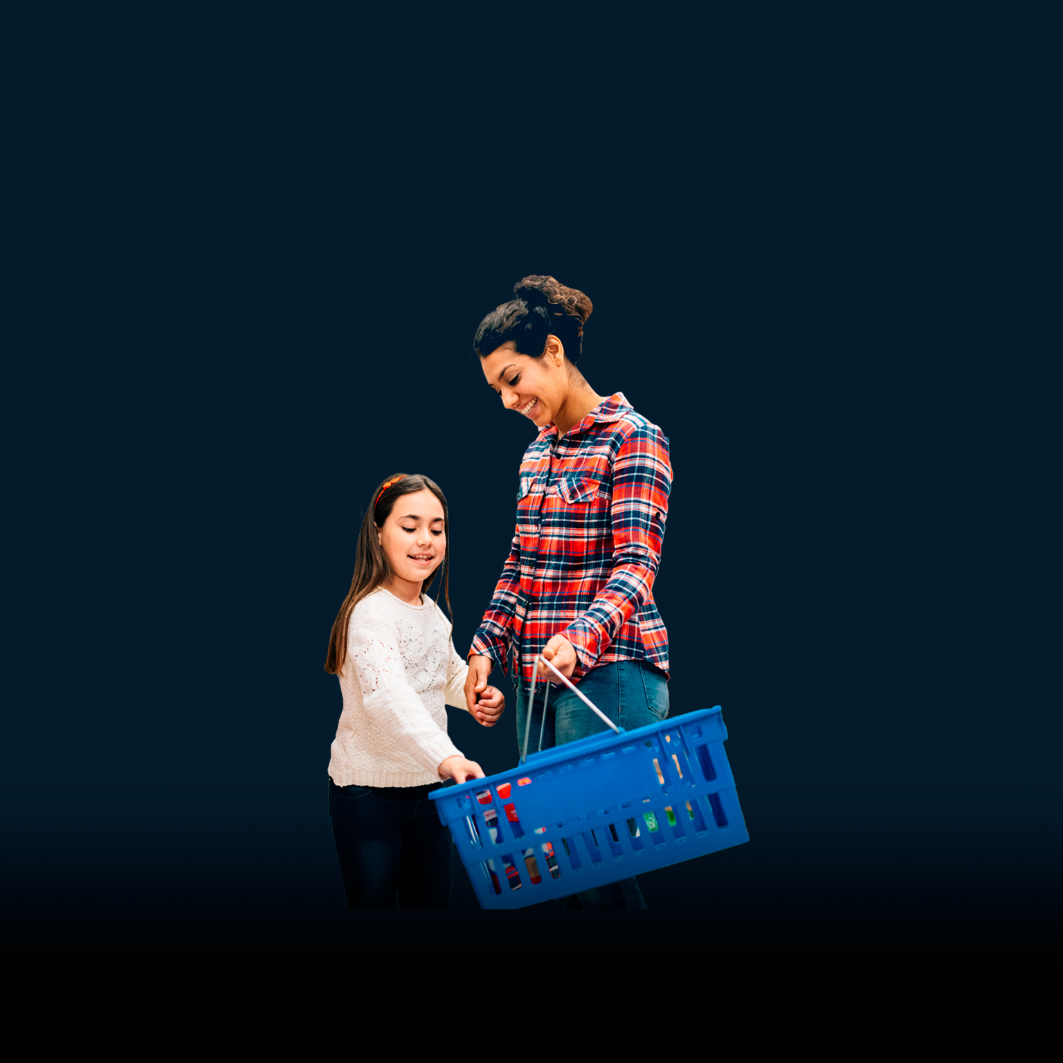 mother holding grocery basket, daughter placing items in - stock photo