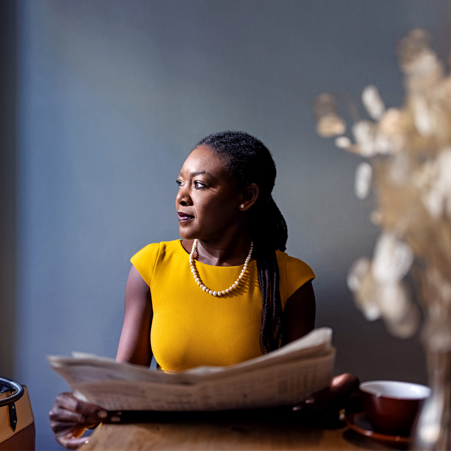 Woman in yellow holding a newspaper