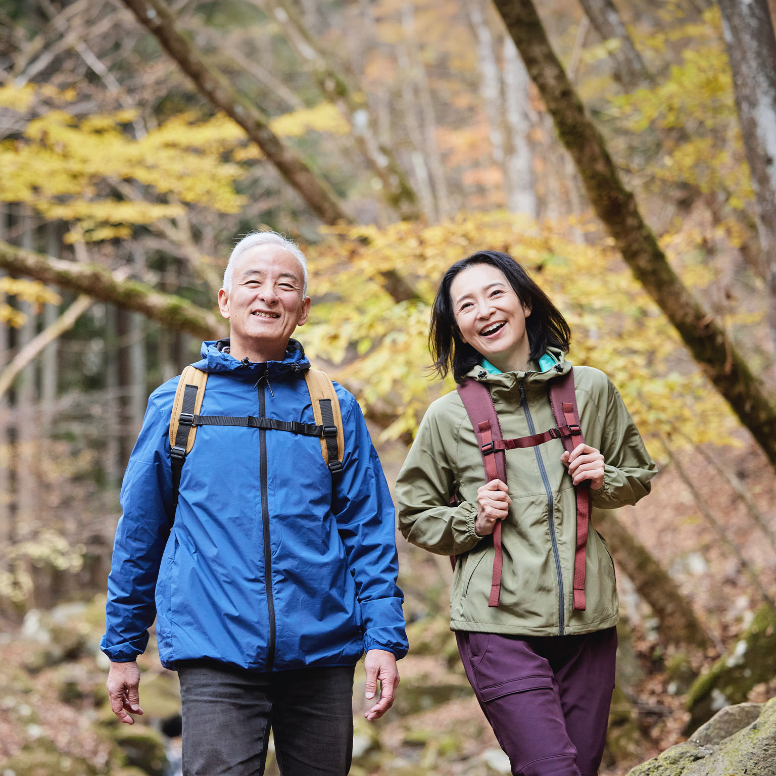 Smiling Japanese senior couple hiking in an autumn forest