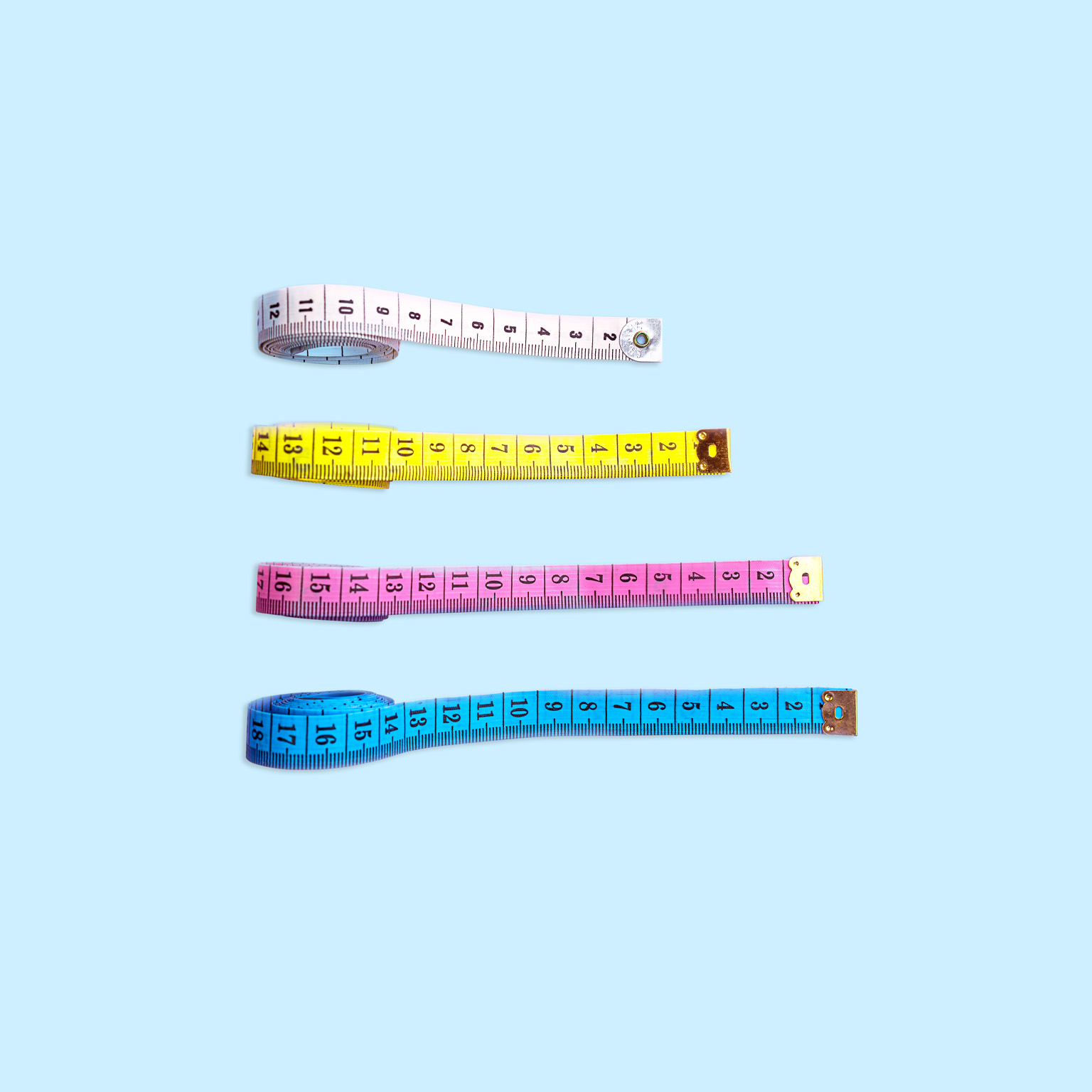 Four measuring tapes are positioned vertically on a light blue backdrop. Each tape is stretched out to varying lengths and placed in increasing order from the longest to the shortest.