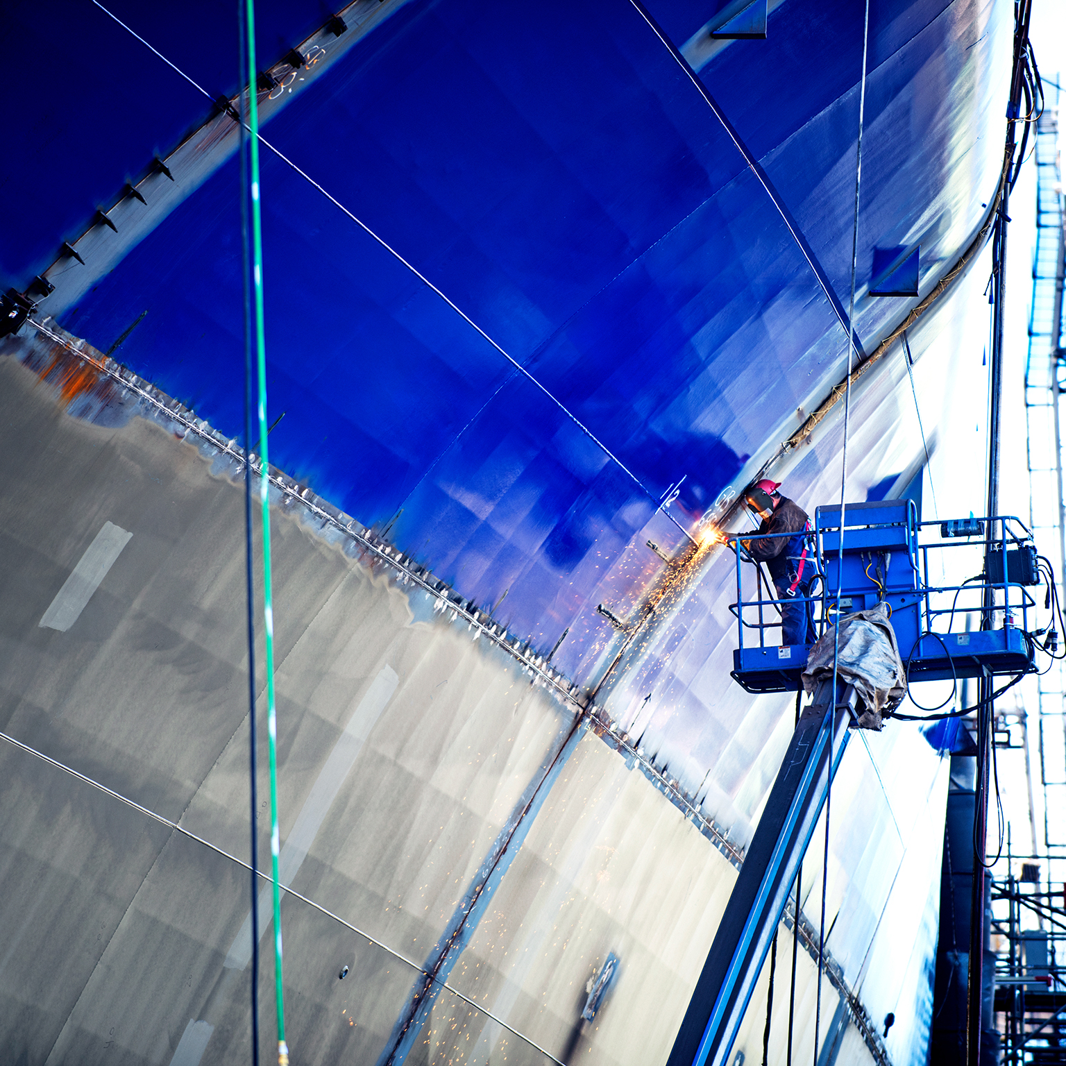 Low angle view of worker welding ship at industry