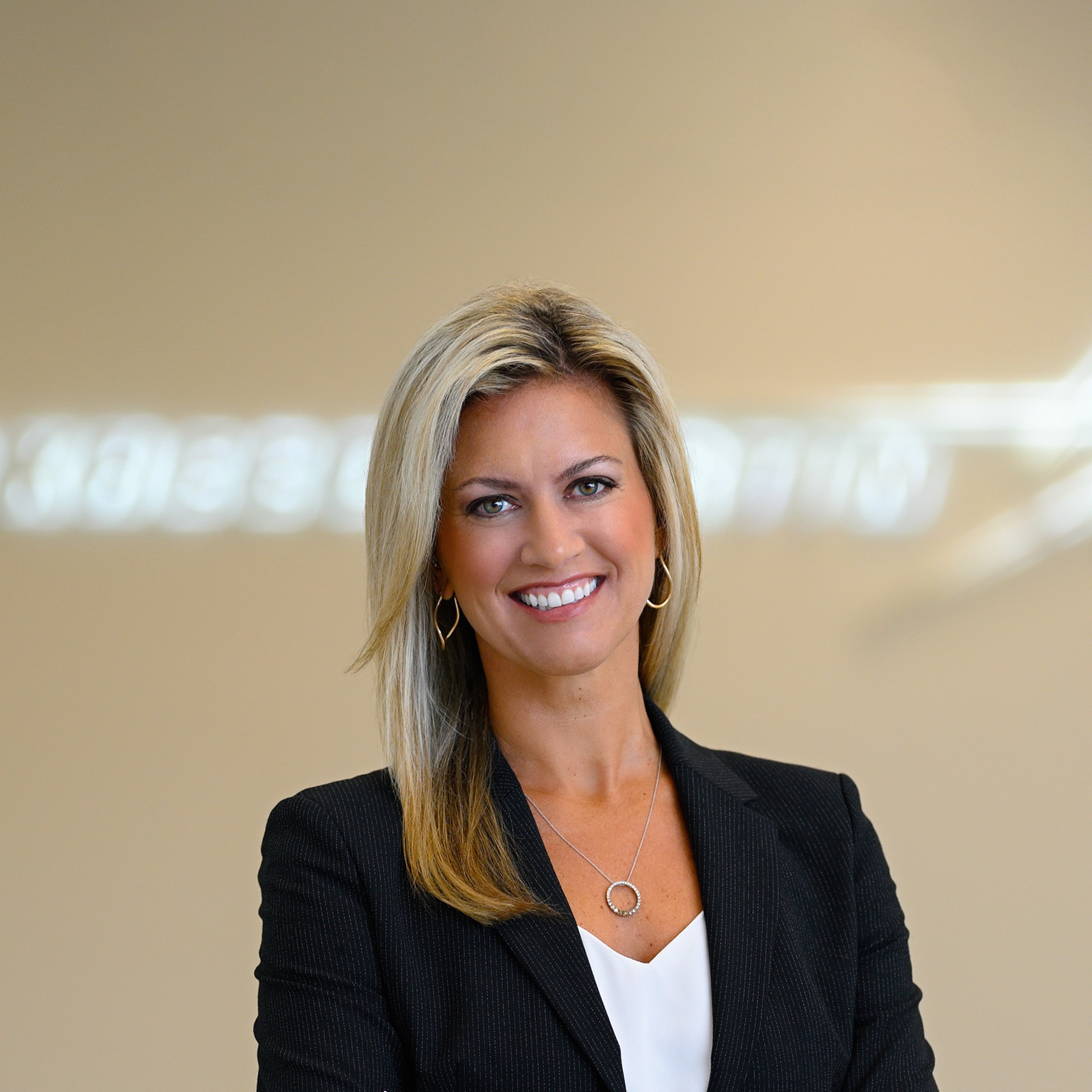 Portrait of Stacy Kubicek, who is wearing a sports jacket and exuding confidence. The Lockheed Martin logo is visible in the background, albeit slightly blurred.