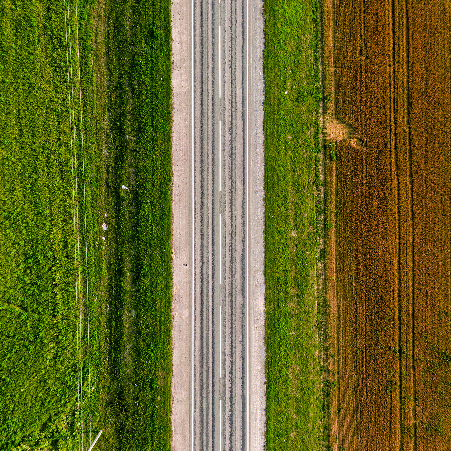 Aerial shot of an empty highway on a green and brownfield