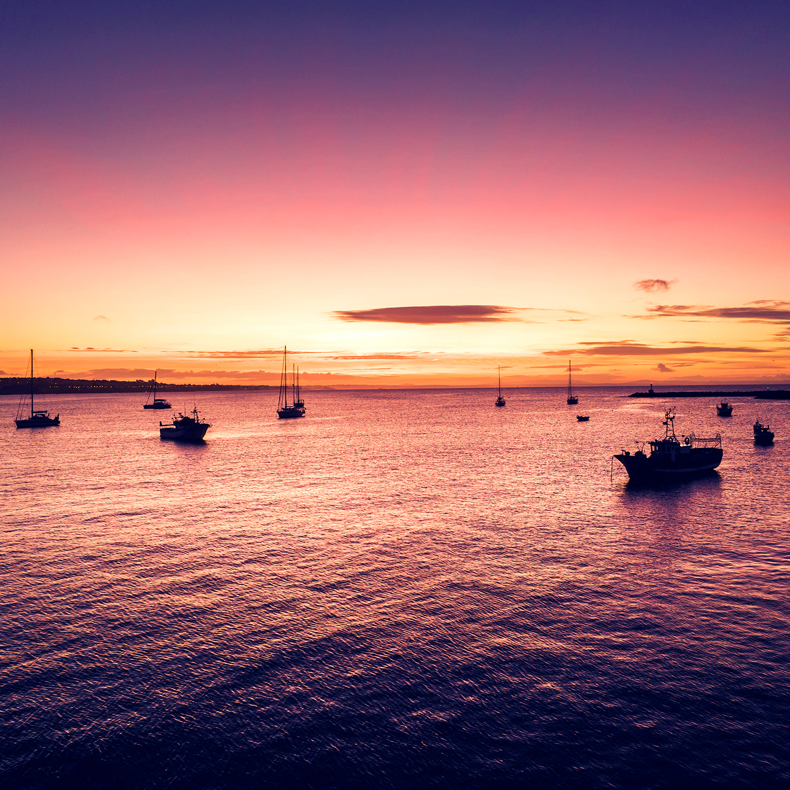 Aerial view of boats and ships in the sea near the port in Cascais, Portugal during sunset