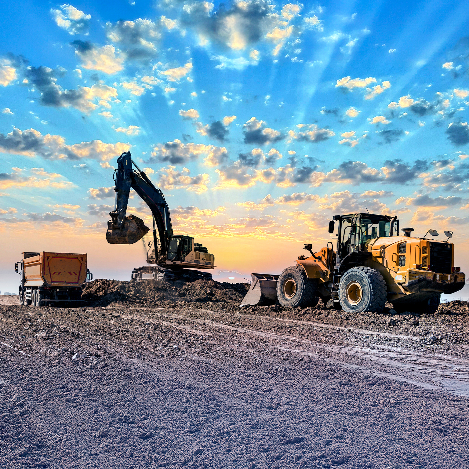 Excavators working on construction site at sunset