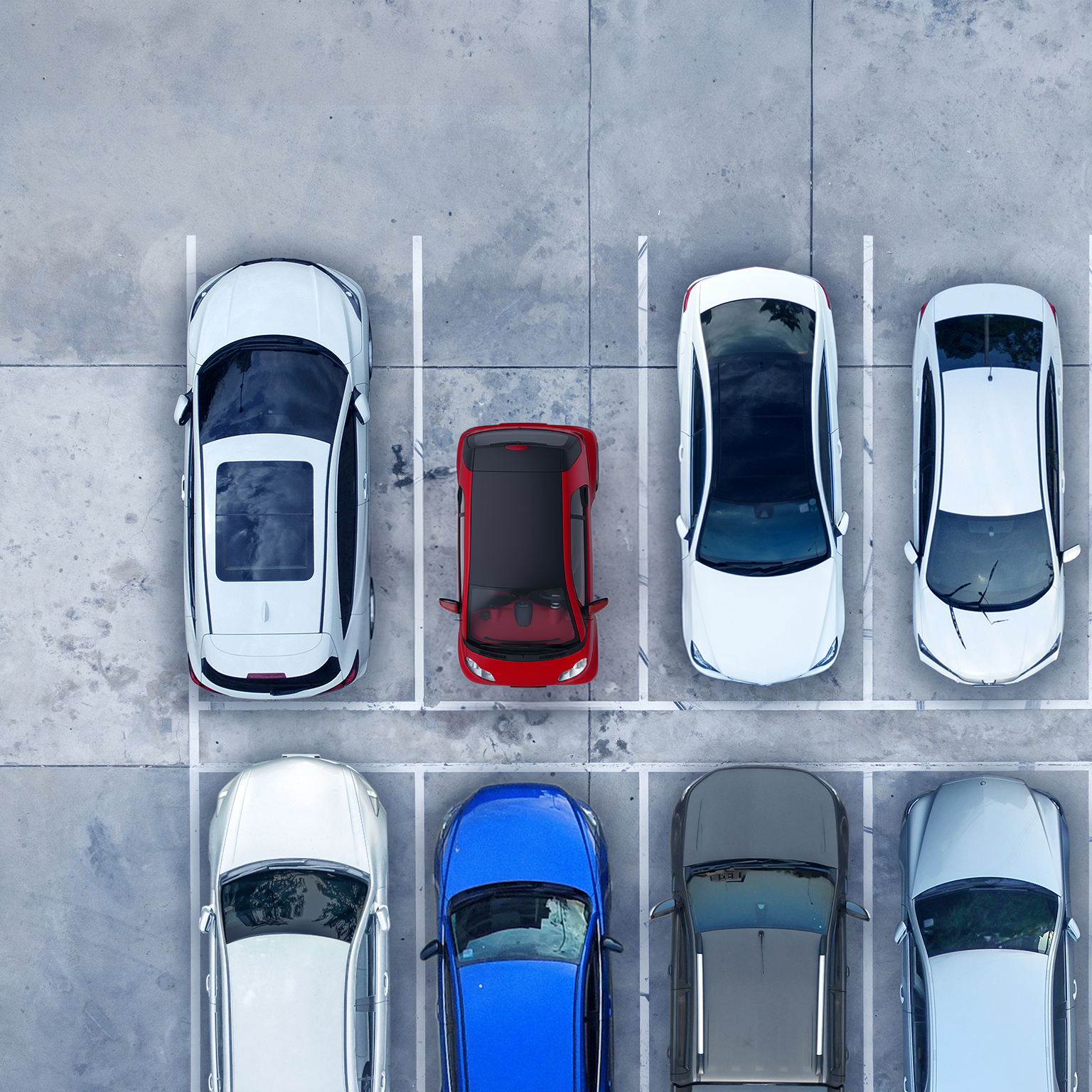 An overhead view of a red, ultra-light microcar parked among 7 full size vehicles highlighting the contrasts in size and space between them