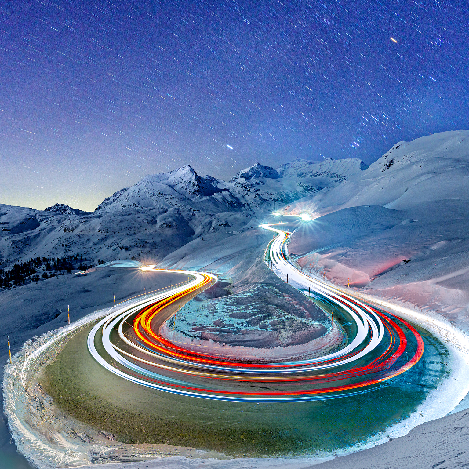 Car trail lights on snowy mountain road