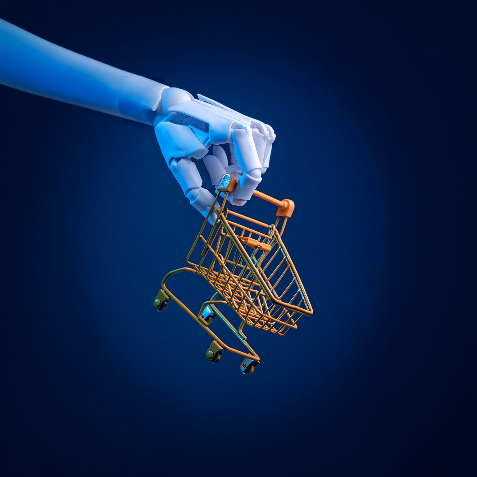 Robotic hand holding a miniature shopping cart: concept of e-commerce, automation and AI retail