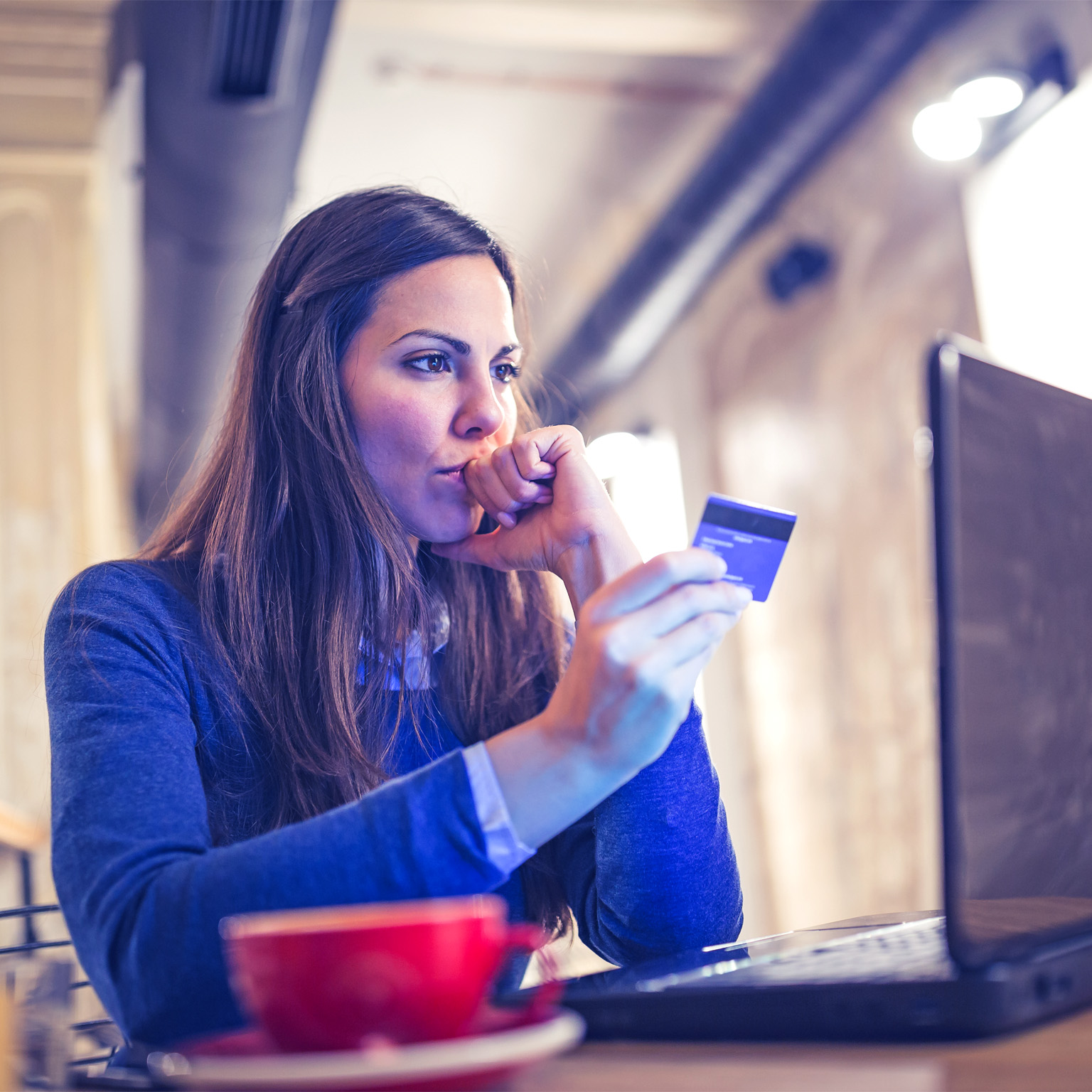 Image of a woman with a concerned look on her face shopping online and paying with card.