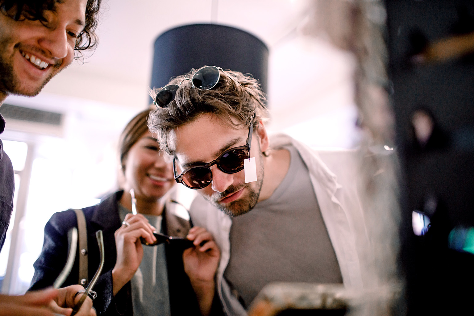 Image of a group of young adult friends trying on fashionable sunglasses and smiling.