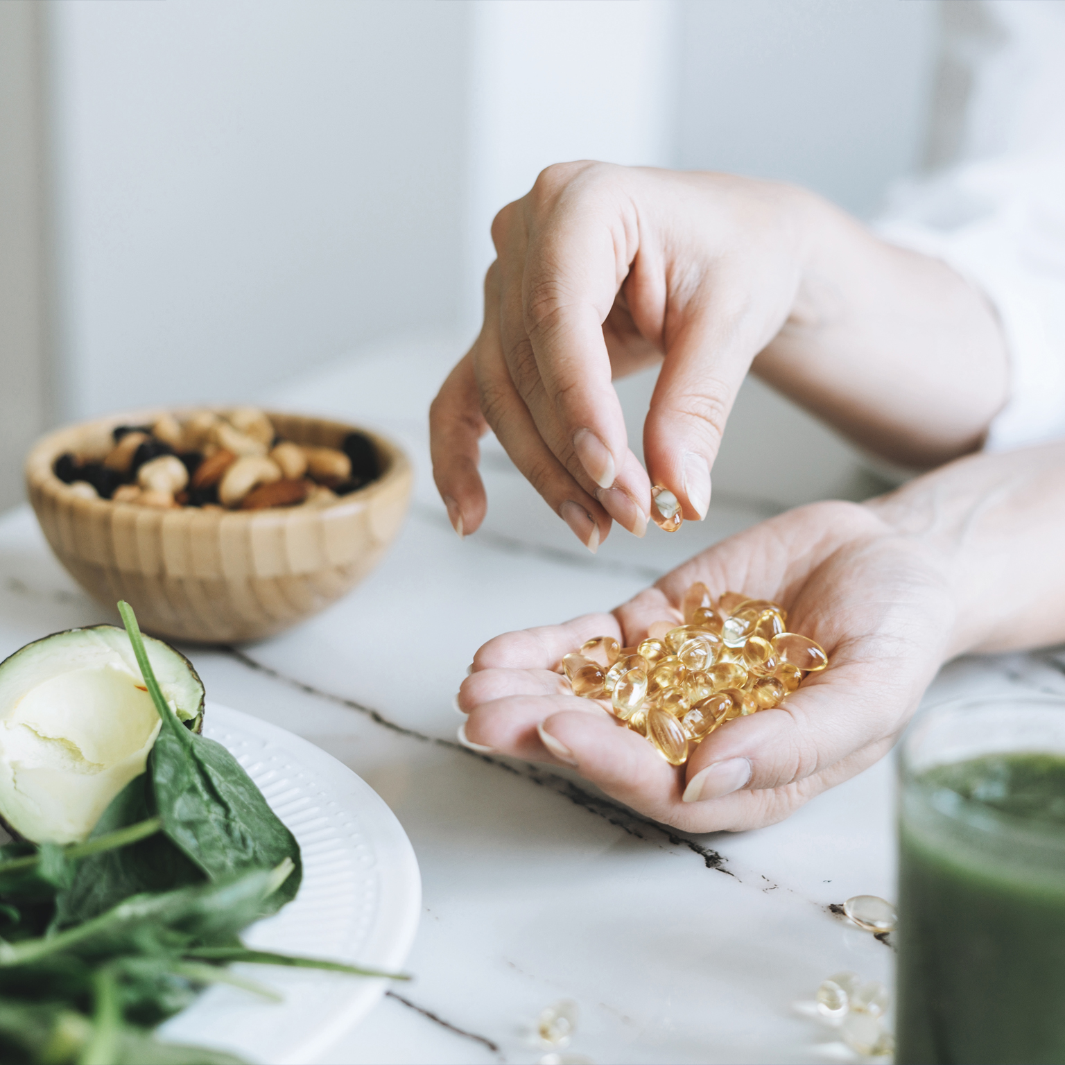 Woman Doctor Nutritionist Hands In White With Omega 3, Vitamin D Capsules With Green Vegan Food