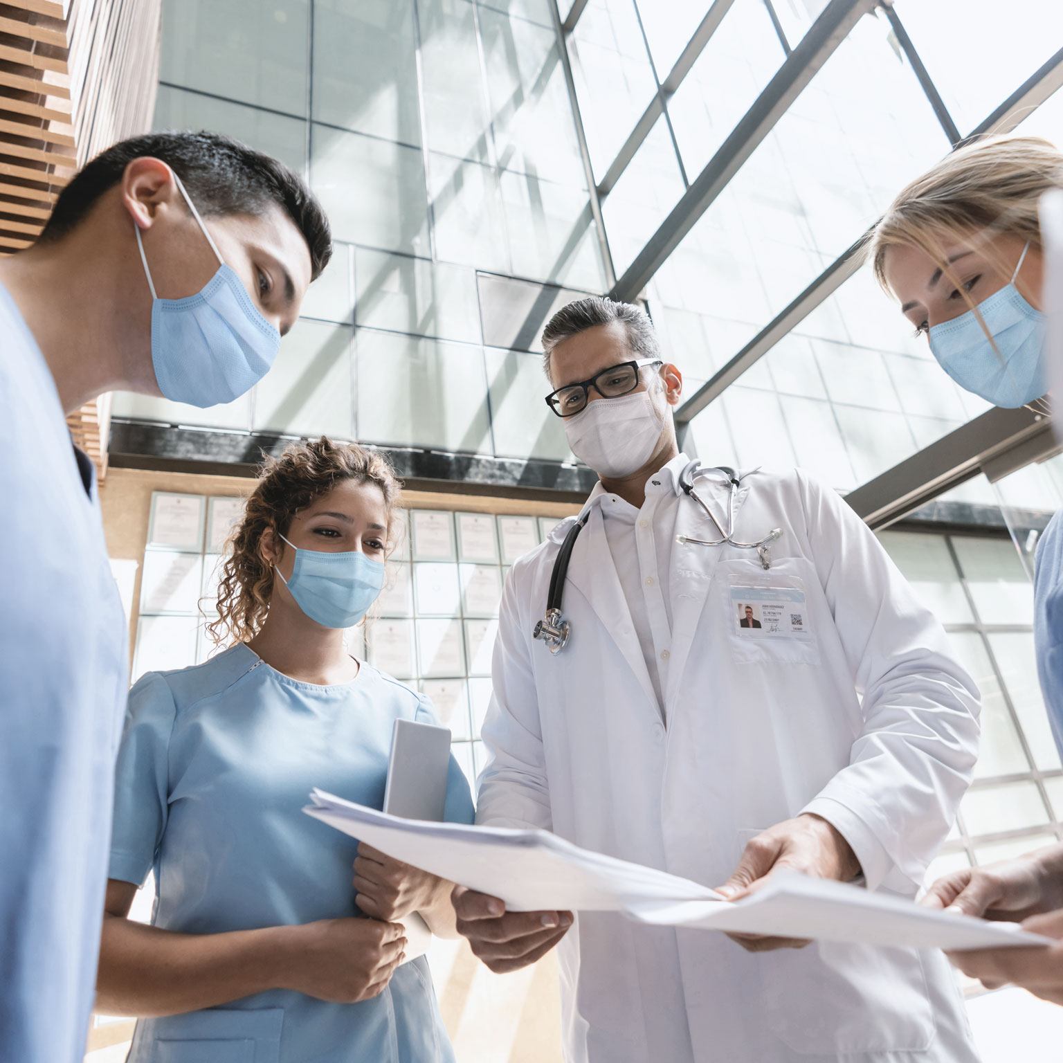 Group of doctors talking at the hospital and wearing facemasks
