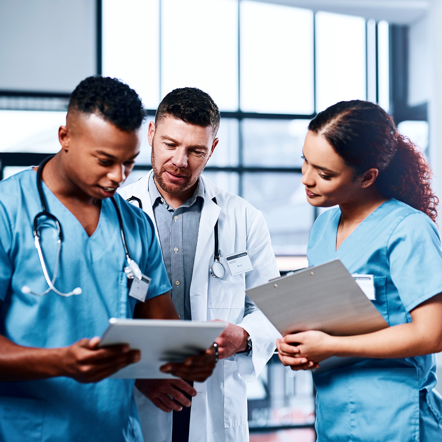 A group of medical practitioners using a digital tablet together in a hospital