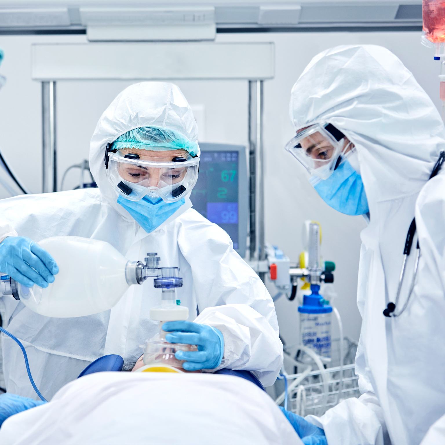 Medical professionals in hazmat suits engaged in procedure using medtech