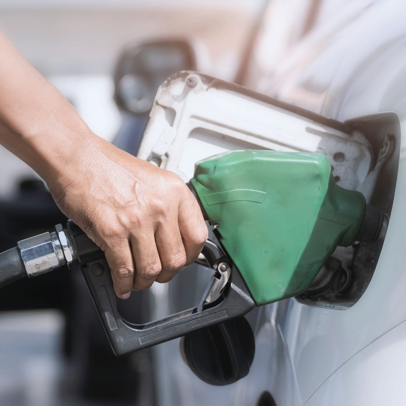 Hand holds fuel nozzle to add fuel in car