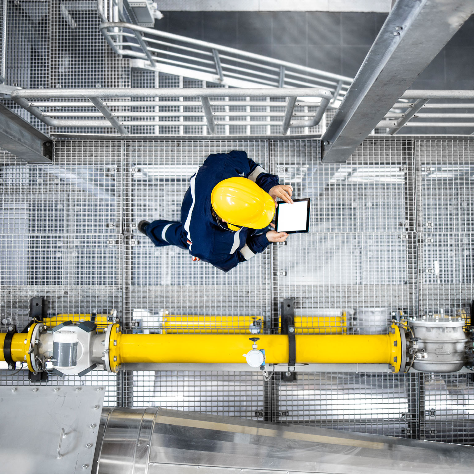 Top view of petroleum refinery worker walking by gas pipes and checking production.