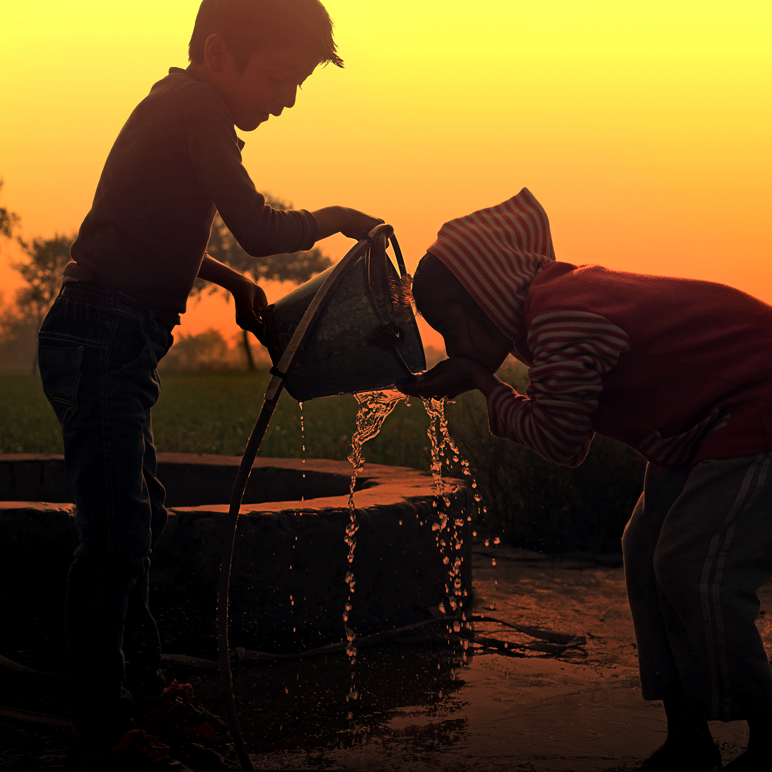 Children drinking water on water well