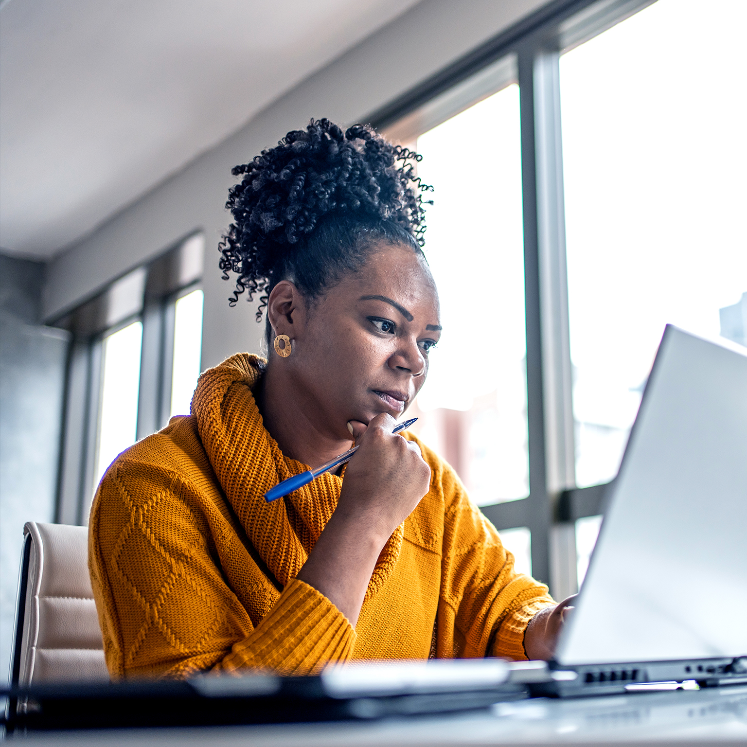 Black woman working from home office and looking pensively at her computer screen