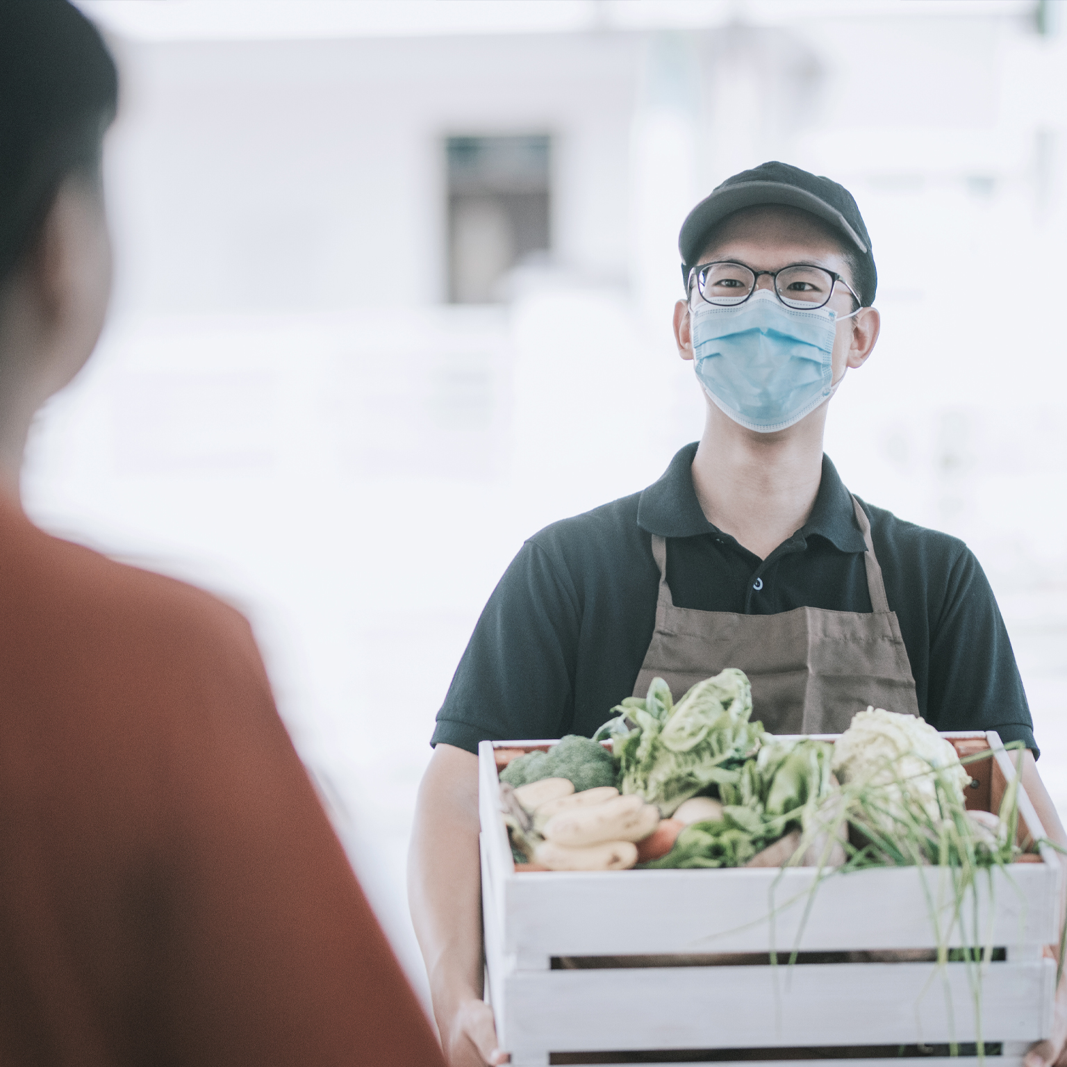 Delivery person handing over a box of vegetables to customer