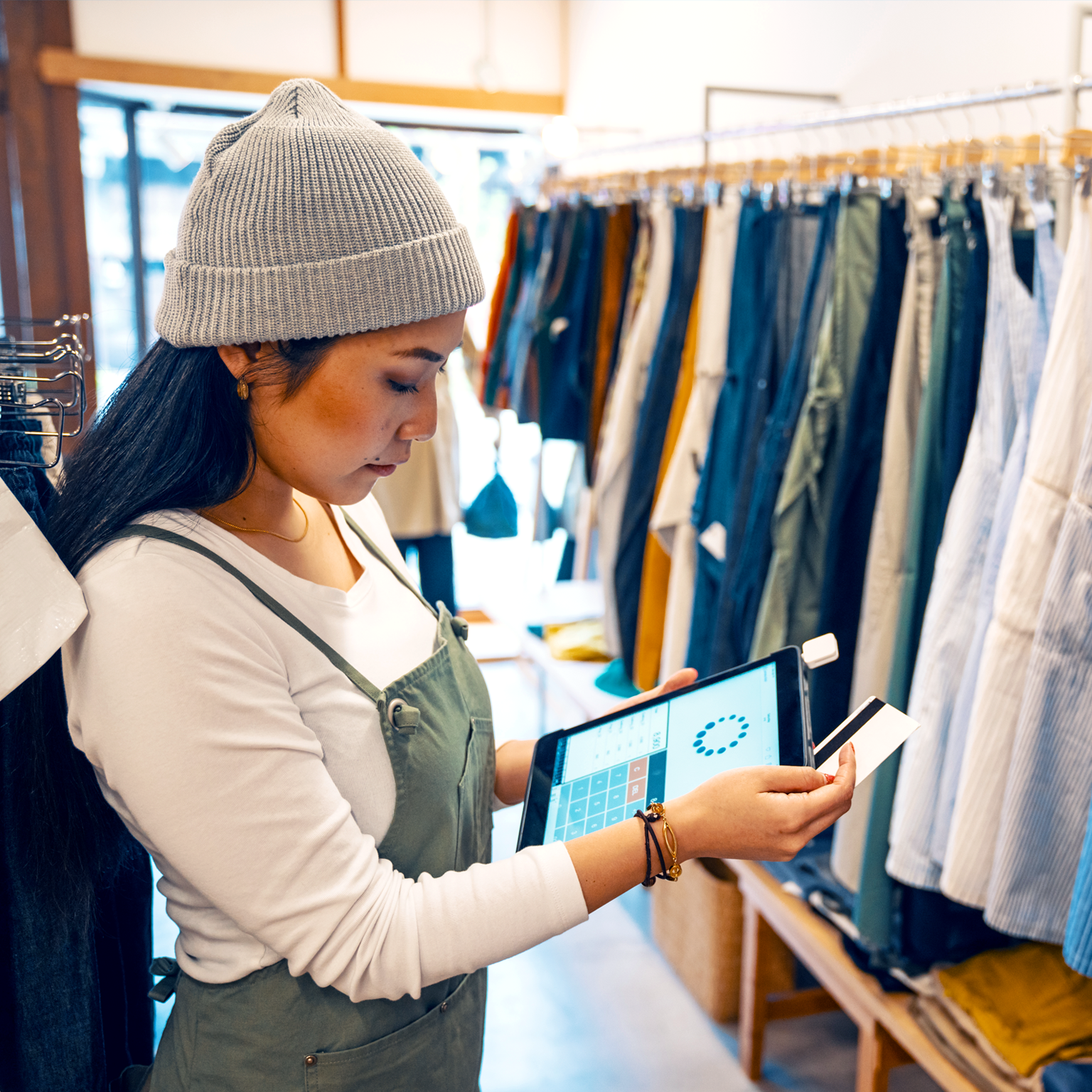 Retail shop clerk taking a mobile credit card payment on a digital tablet in a clothing boutique
