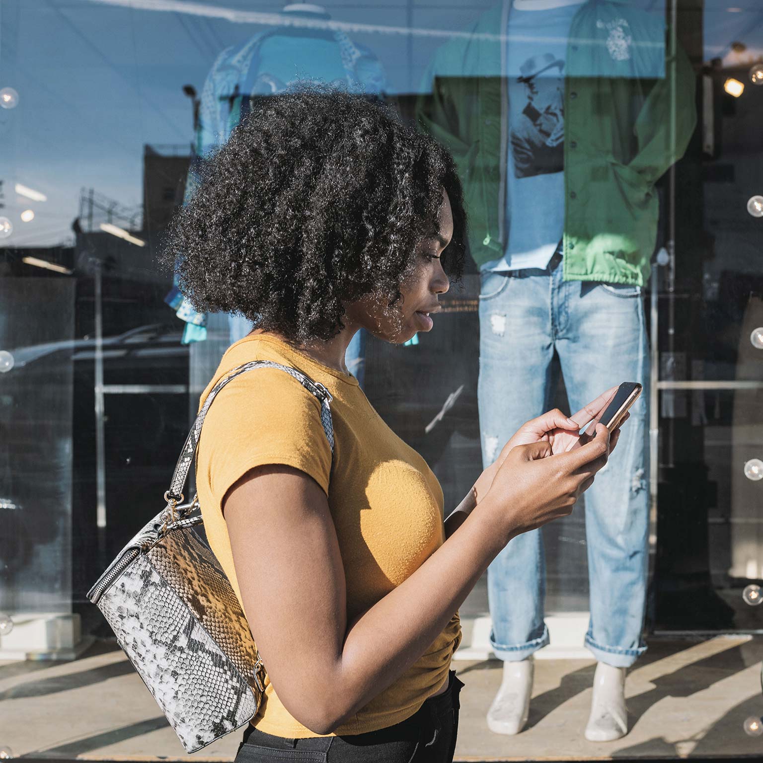 Young woman looking at phone outside shop window