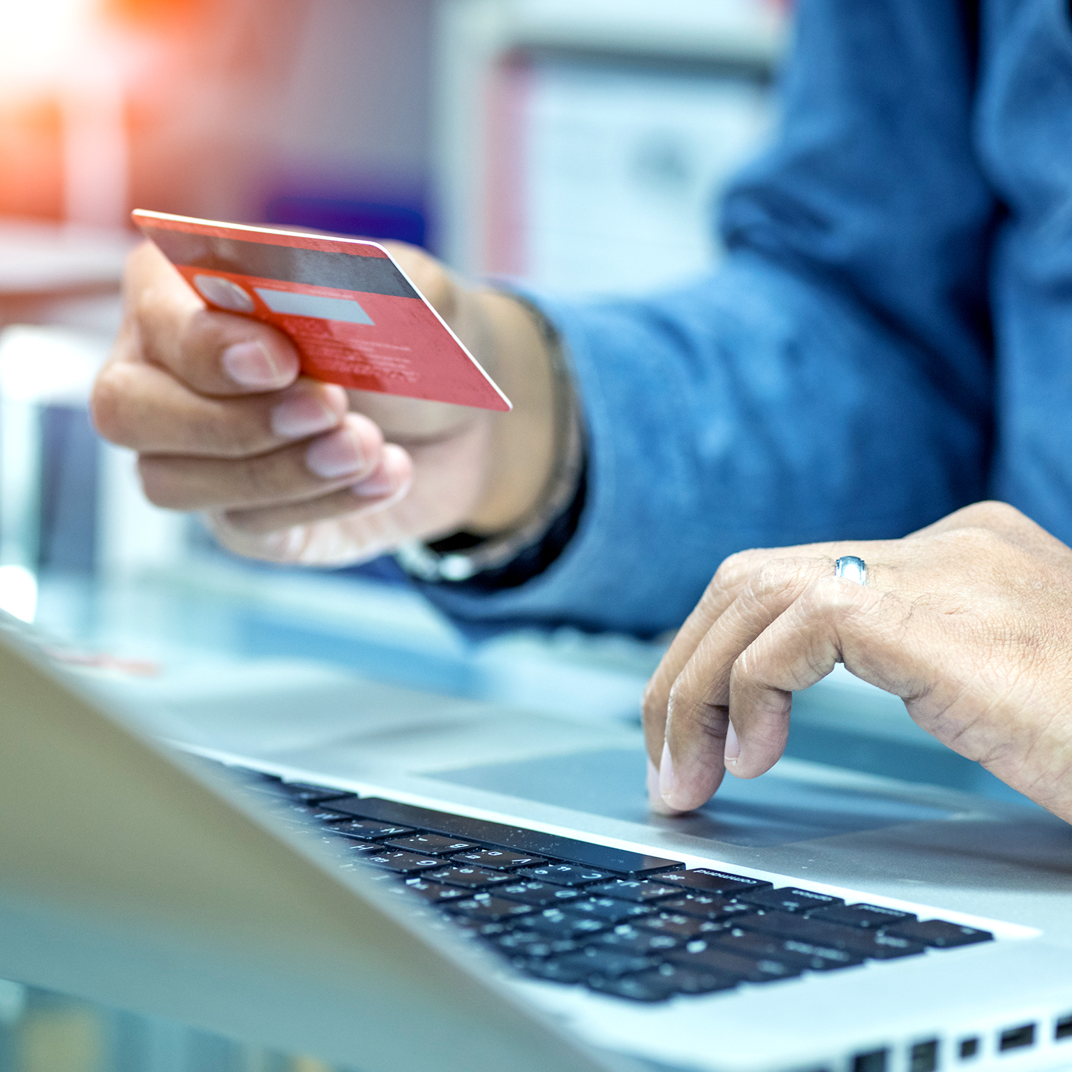 hand holding credit card in the air, other hand clicking laptop while online shopping - stock photo