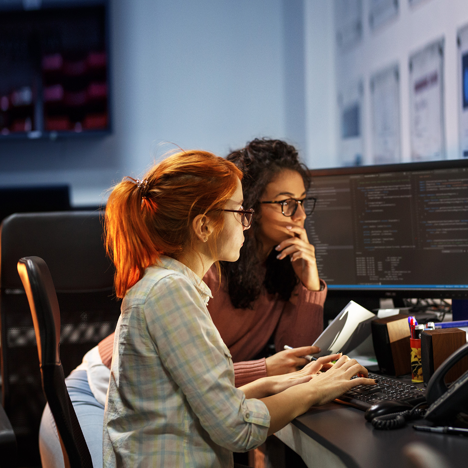 Two female programmers working on new project. They working late at night at the office. - stock photo