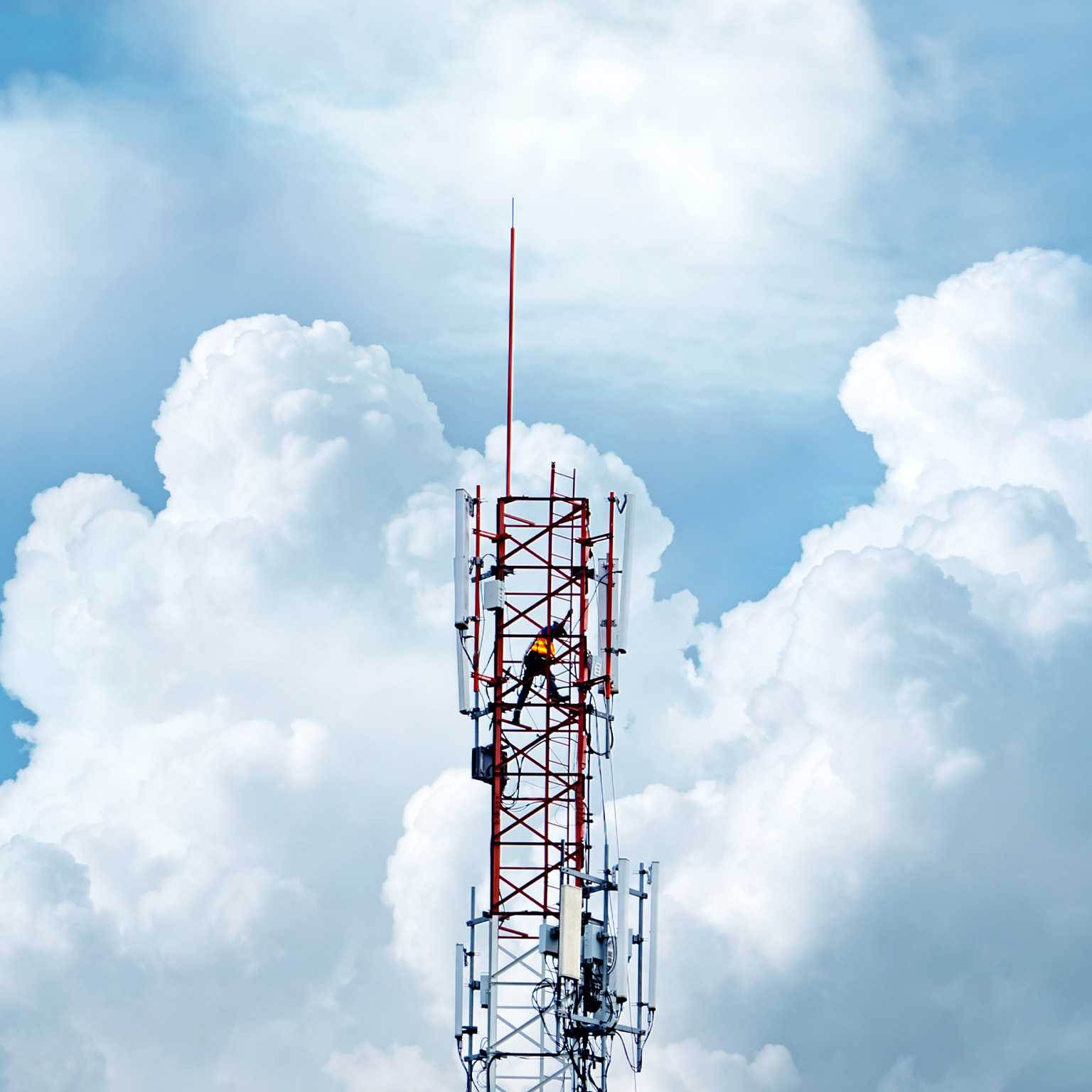 Telecommunication tower with backdrop of blue sky and white clouds