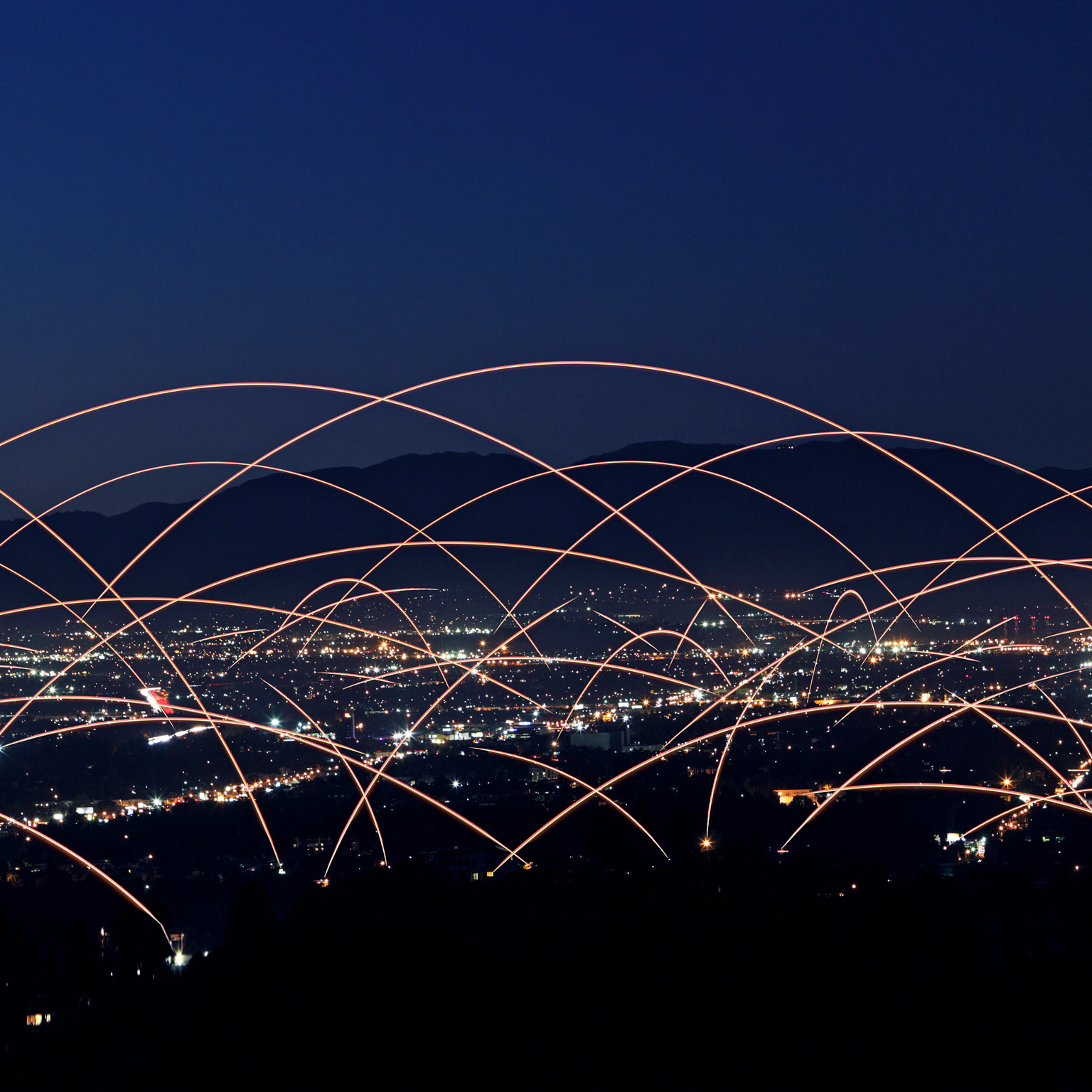 Multiple rays of light connecting buildings to each other across a city skyline