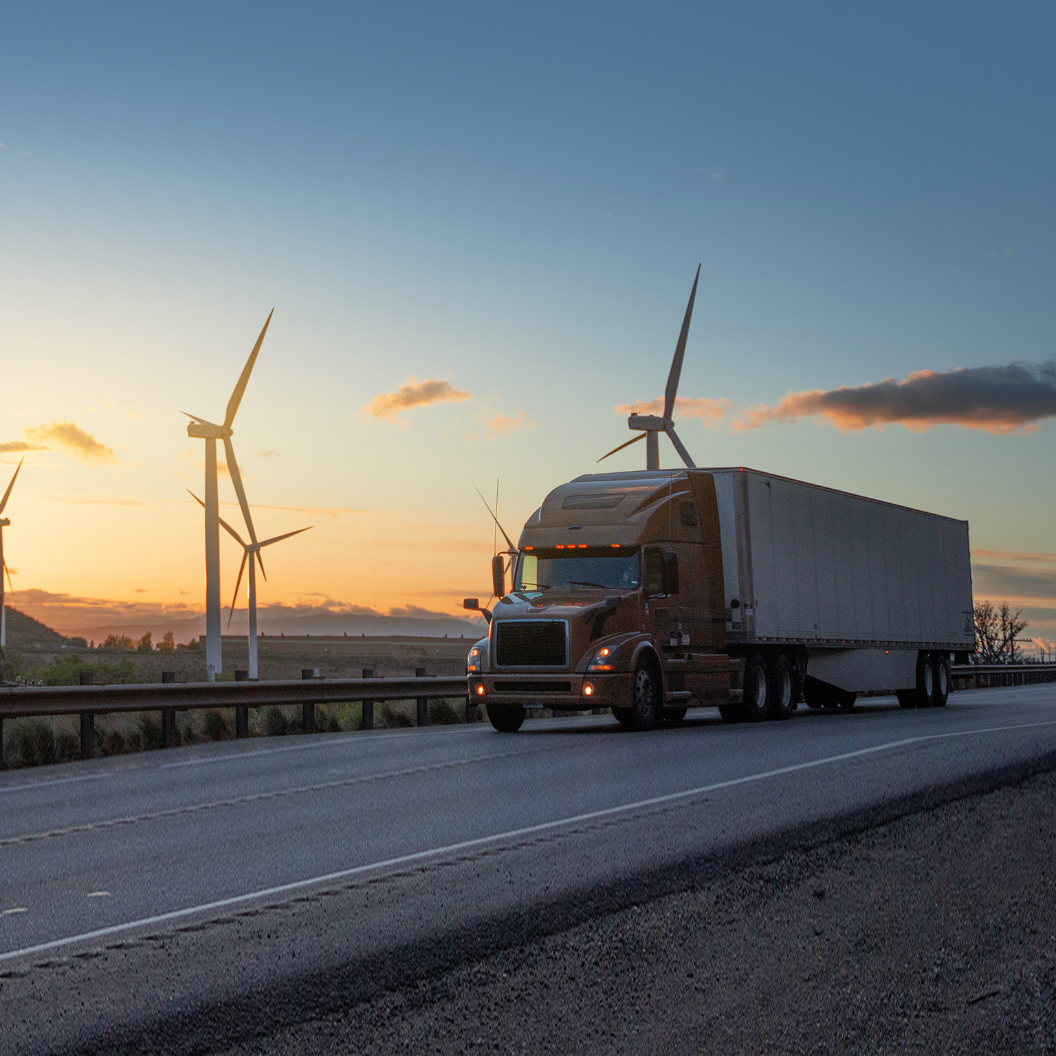 Semi truck speeding in front of Wind turbines in Utah, USA - stock photo
