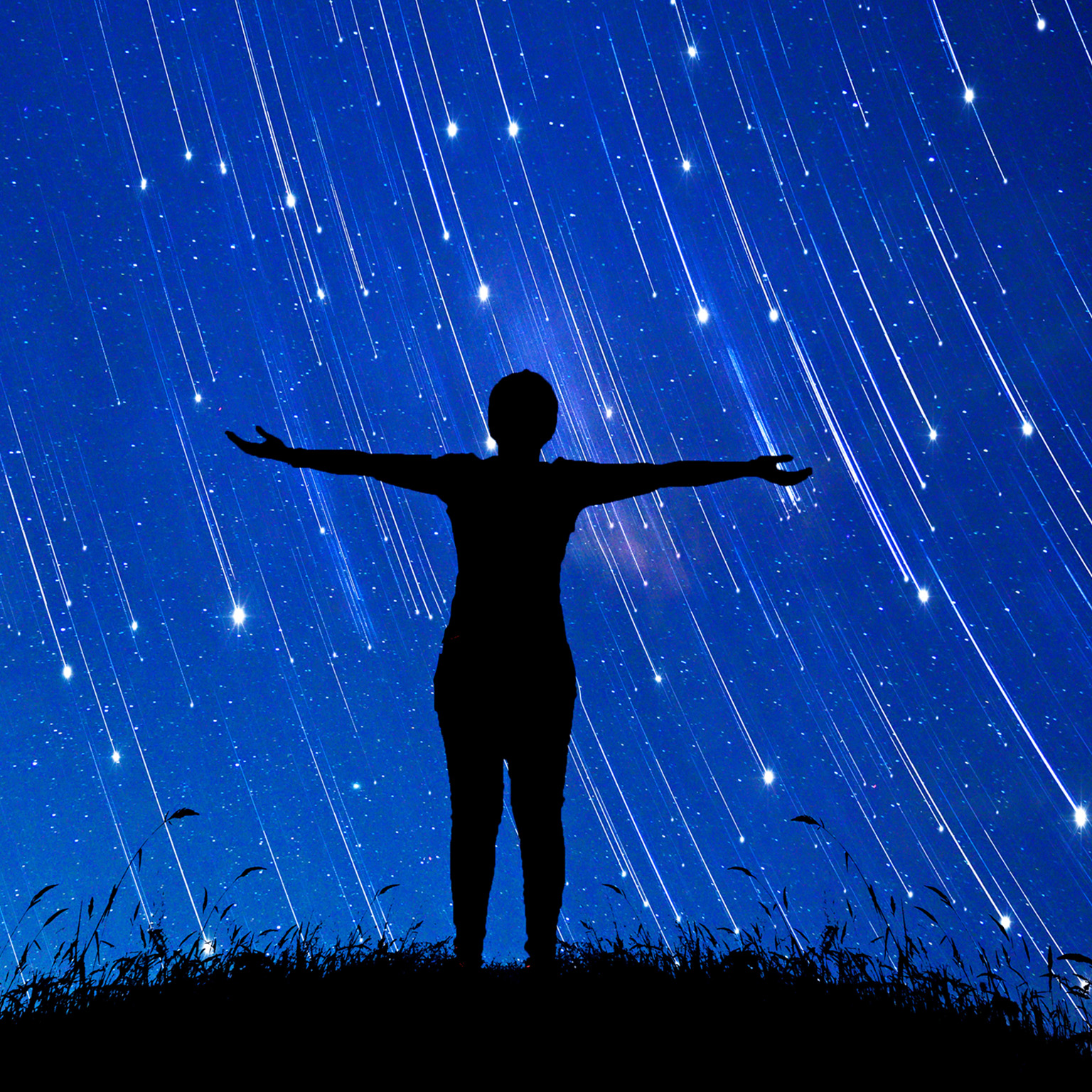 A girl standing with her arms open to a sky full of shooting stars