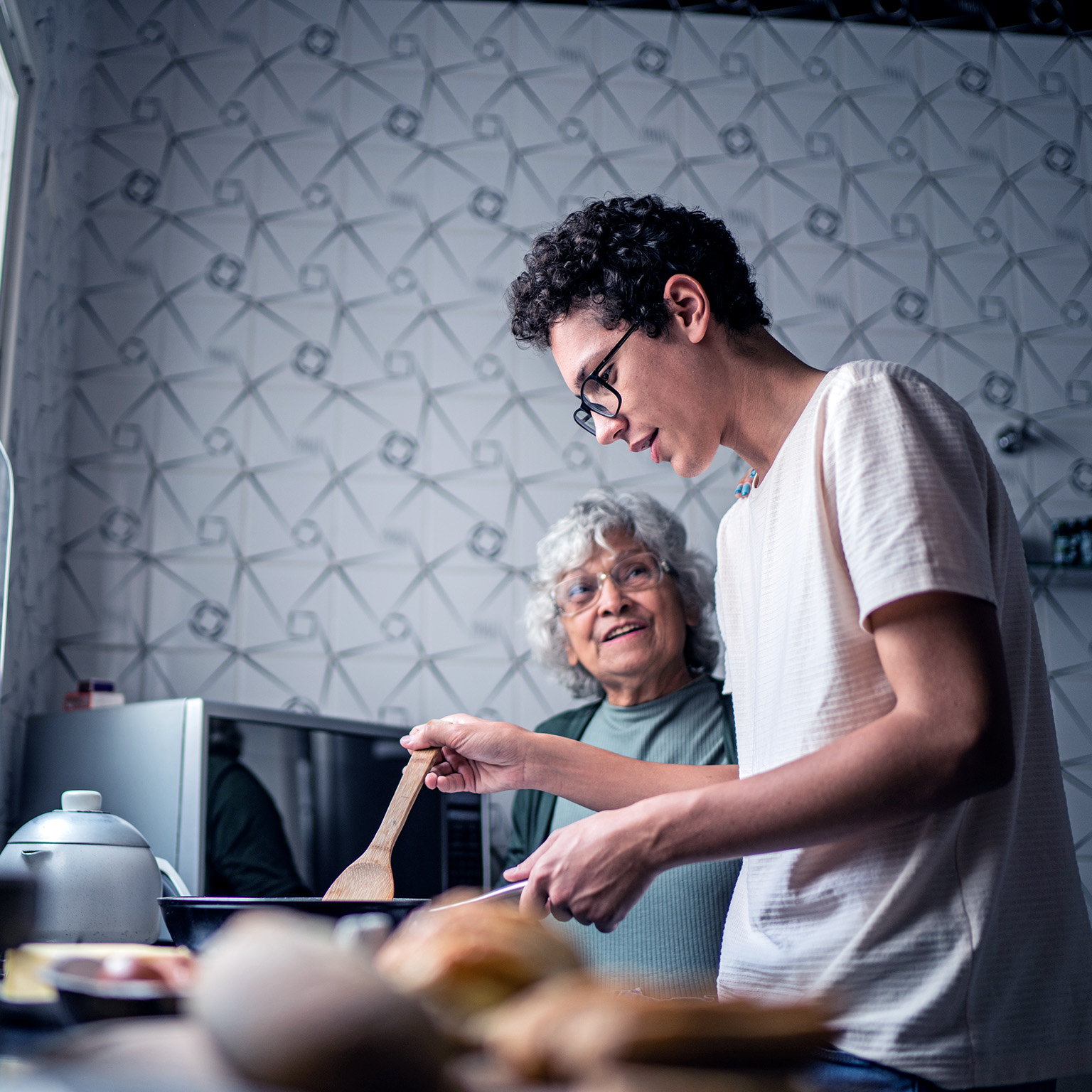 Image of a grandson and grandmother cooking together at home.