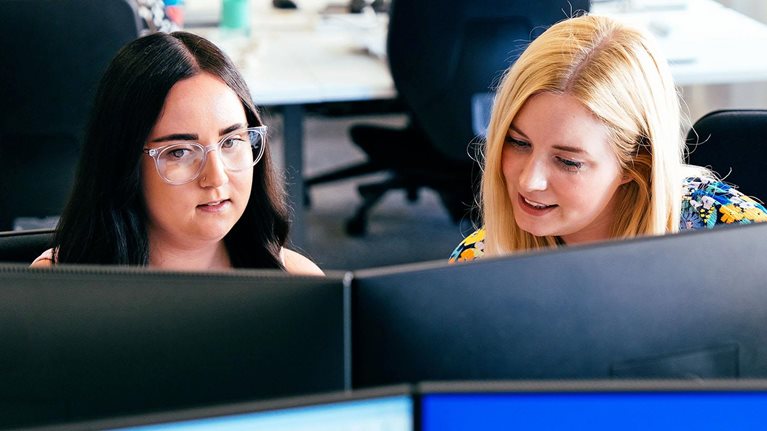 Insurance professionals collaborating at computer workstations in office setting
