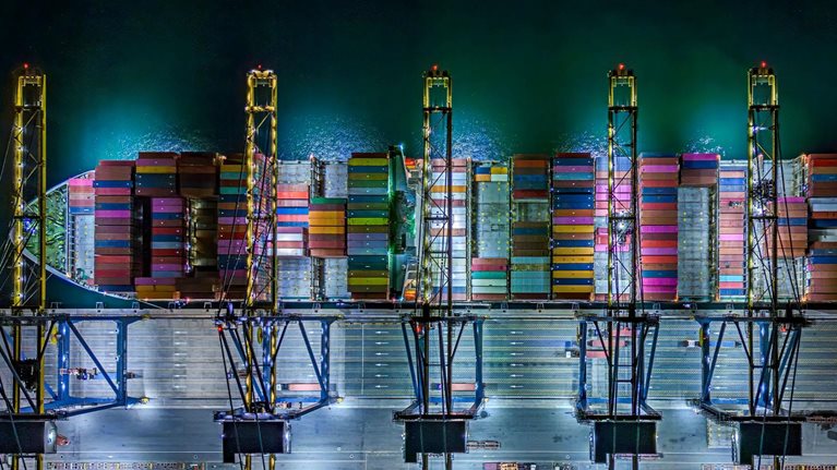Aerial top view of container ships at dock during twilight. - stock photo